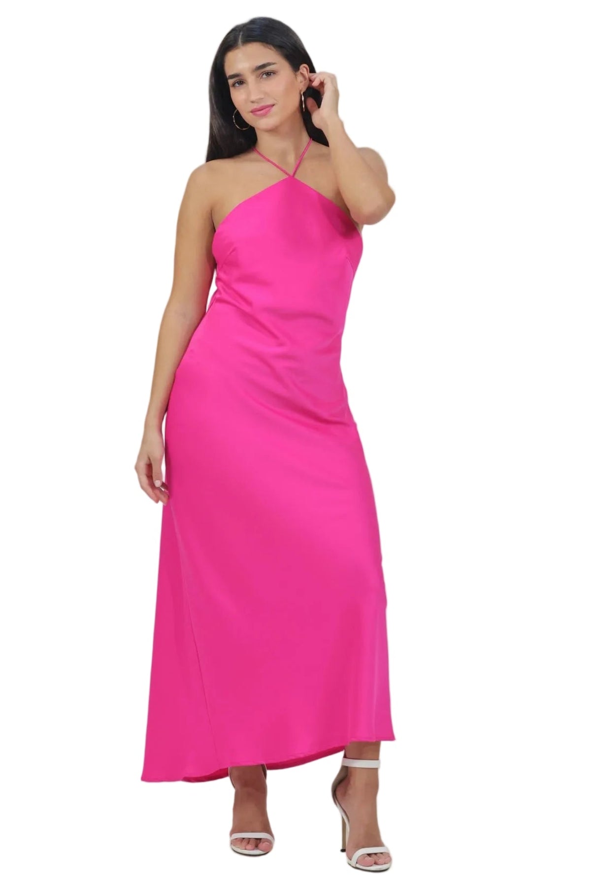 A woman modeling a bright pink one-shoulder maxi dress with a satin-like finish, paired with clear high-heeled sandals, against a solid white background.