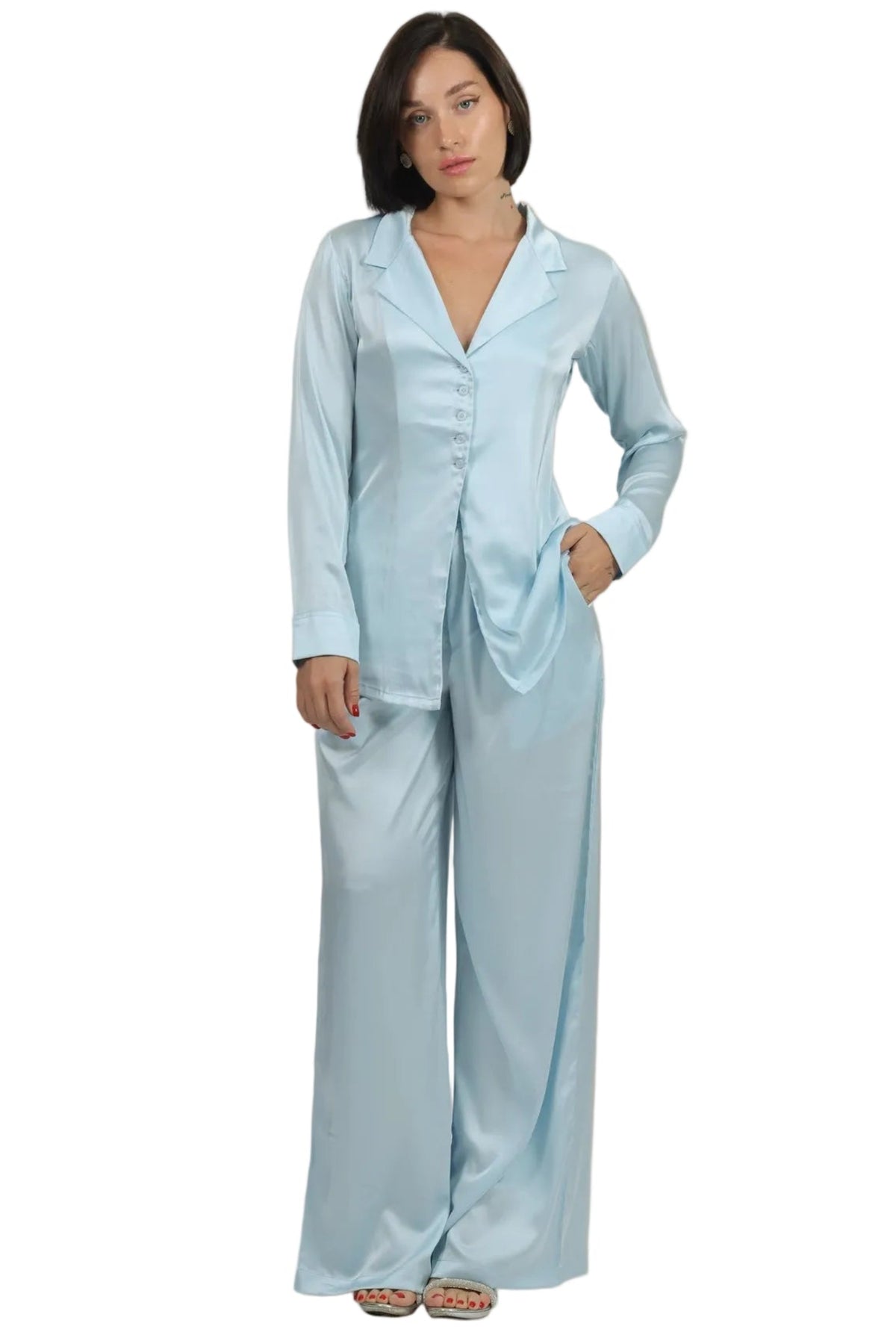 Woman wearing a light blue satin pajama set against a beige background