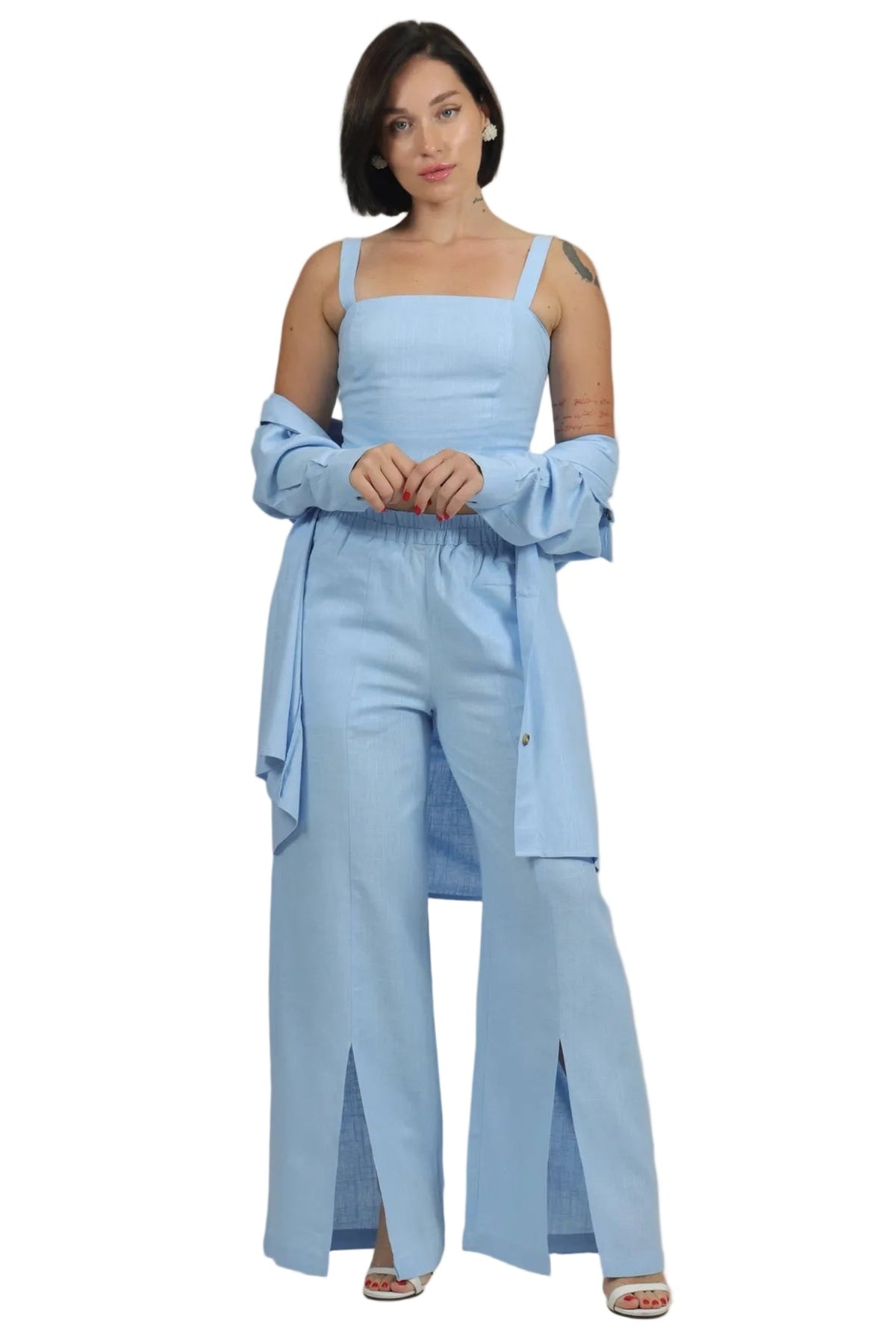 A woman modeling a light blue outfit consisting of a sleeveless top, wide-leg pants, and a matching oversized shirt draped off her shoulders, set against a plain white background.