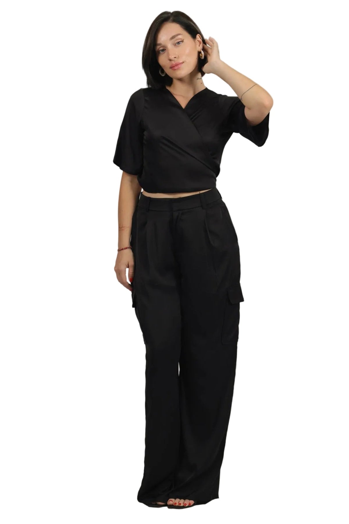 A woman modeling a black short-sleeve wrap-style top and matching black wide-leg pants against a plain white background.