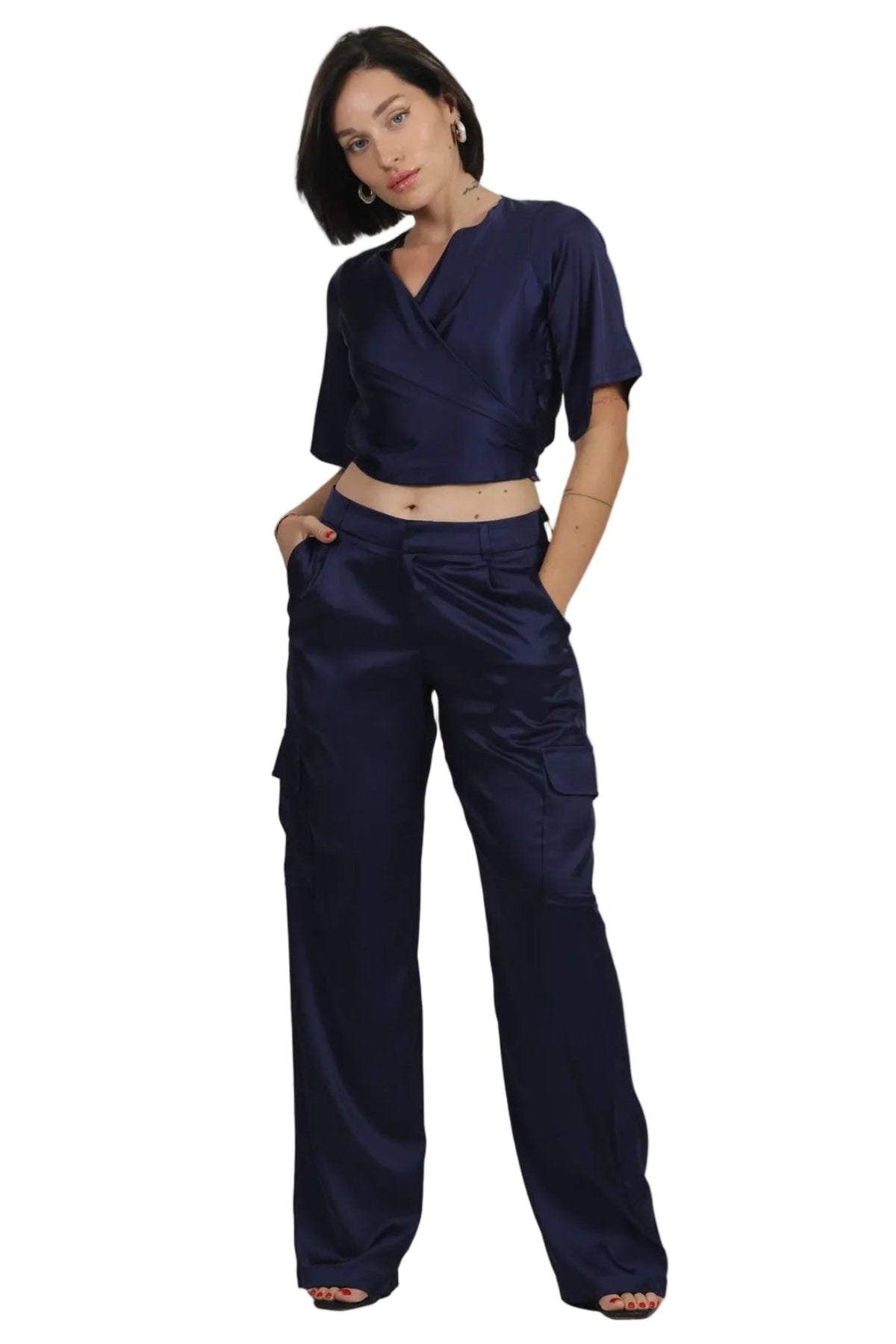 A woman modeling a matching navy blue two-piece set consisting of a short-sleeve cropped V-neck top and high-waisted cargo pants, shot against a solid white background.