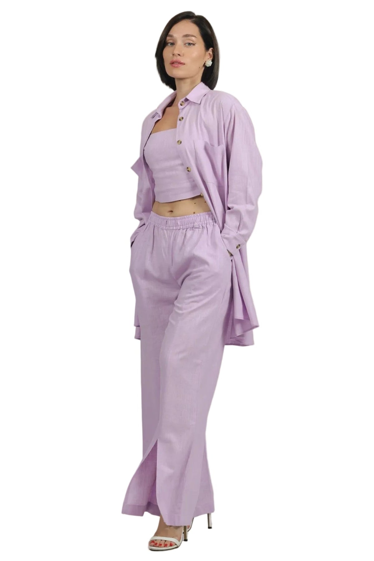 A model wearing a light purple/lavender two-piece outfit consisting of a cropped tank top and matching wide-leg pants, styled with an oversized matching button-up shirt and silver high-heeled sandals, set against a plain white background.