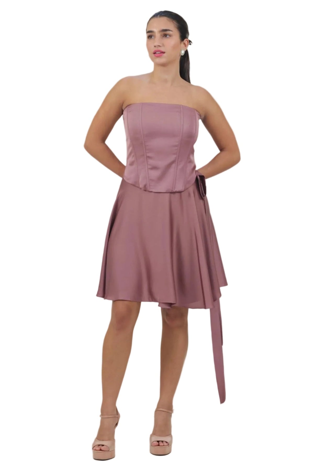 Woman wearing a strapless pink dress with a belt on a beige background