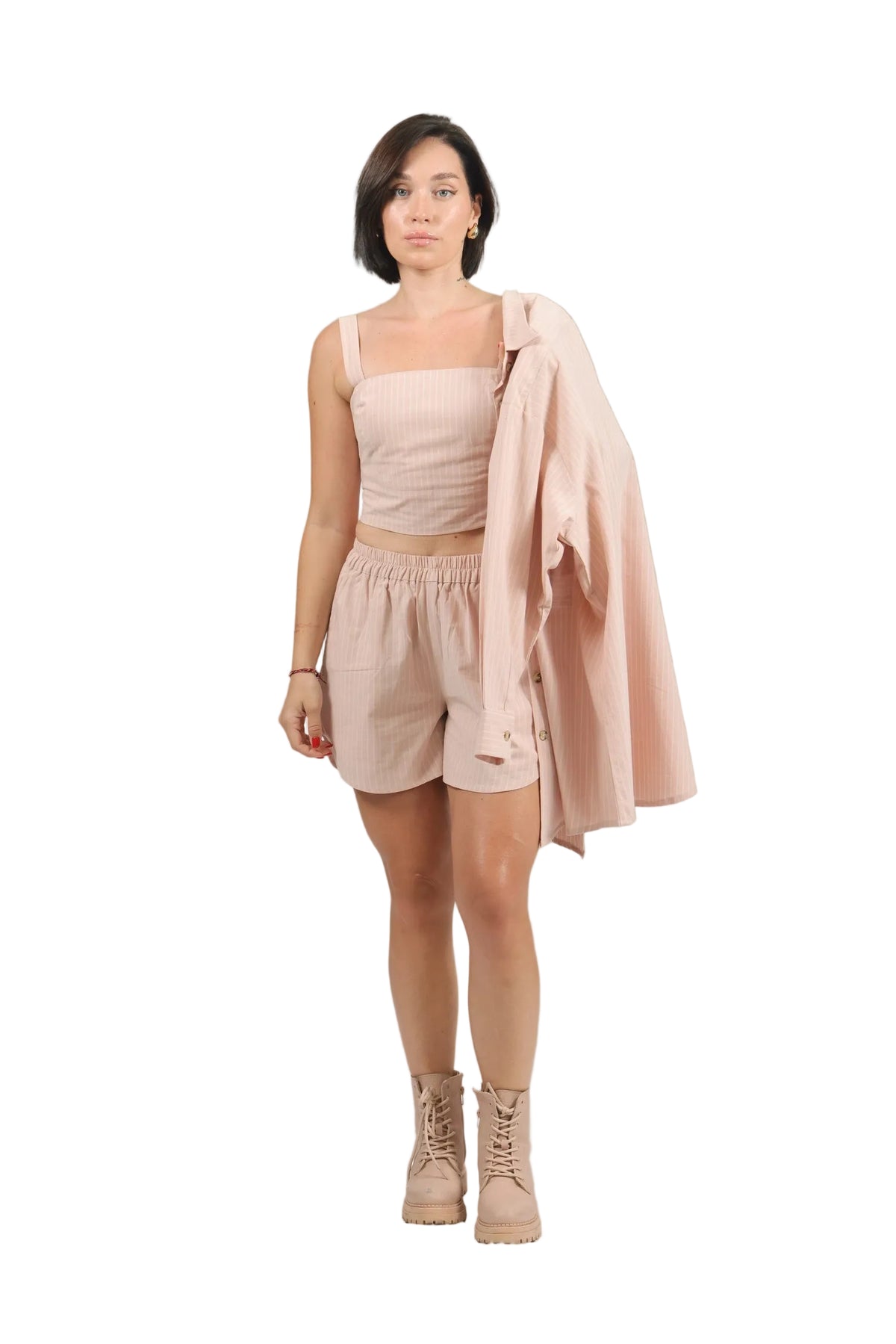 Woman wearing a light pink outfit with a matching jacket on a beige background