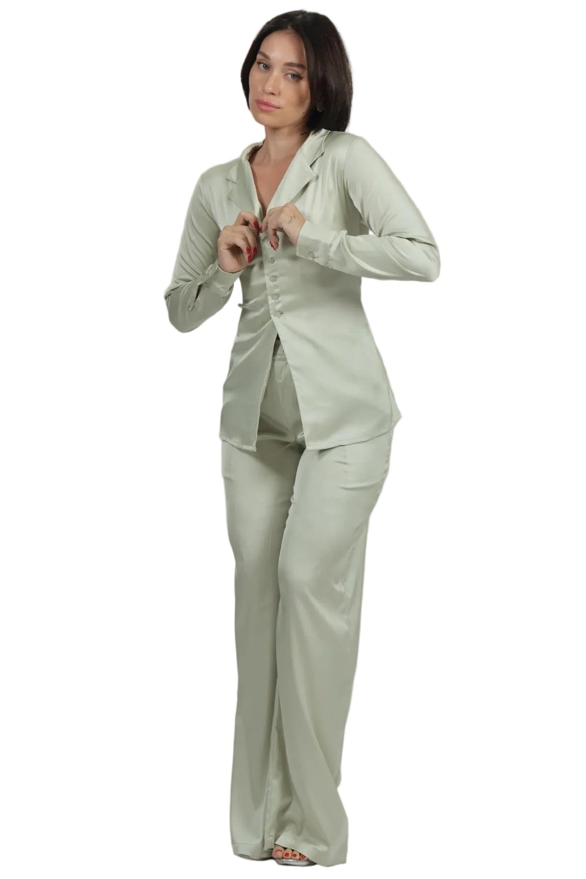 A woman modeling a light sage green two-piece pajama set consisting of a long-sleeve button-up shirt and matching pants, set against a plain white background.