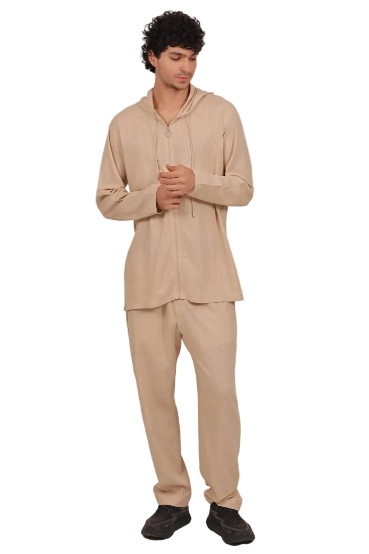 Person wearing a beige hoodie and pants set on a plain background