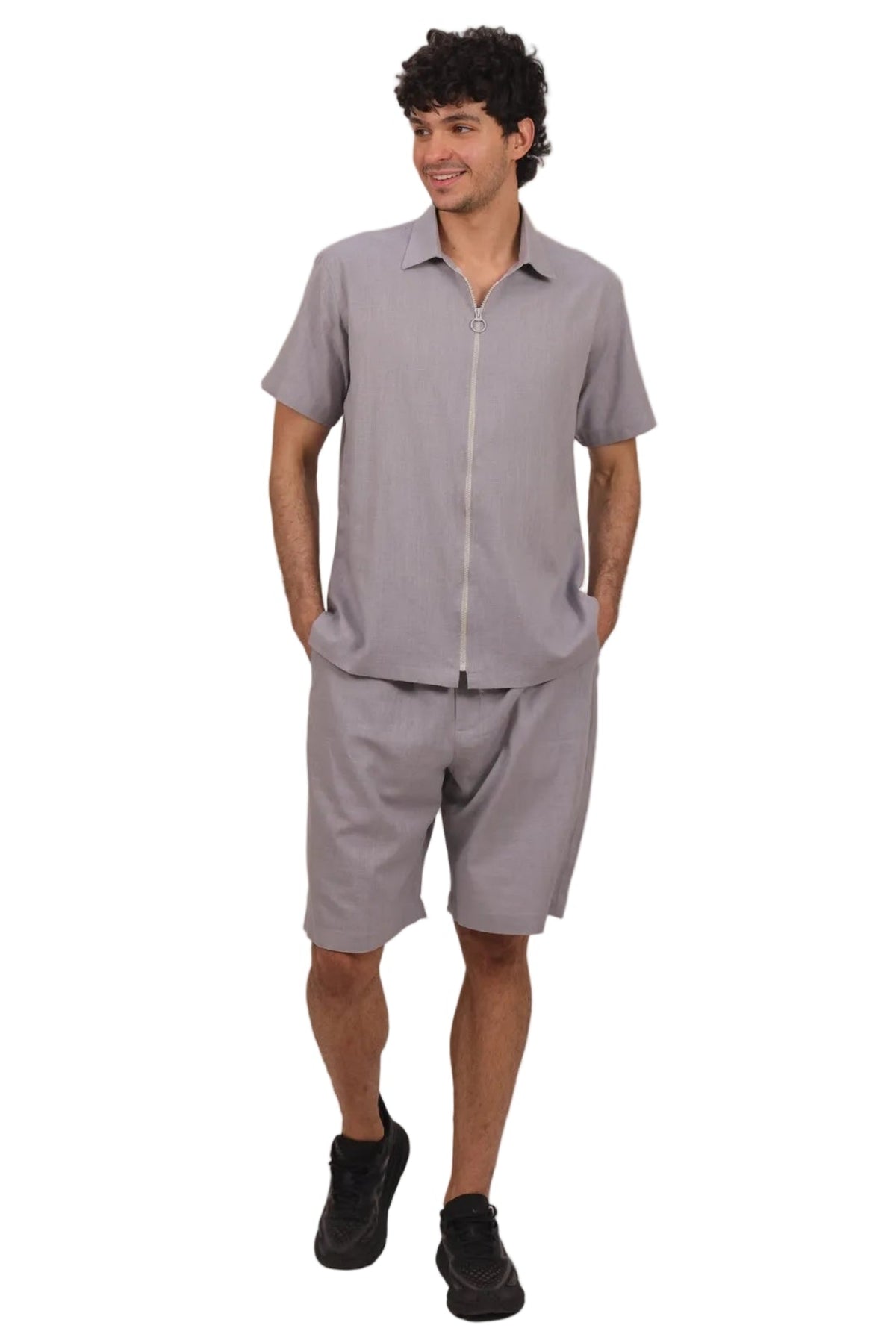 A man modeling a light gray short-sleeve button-up shirt and matching shorts set, paired with black sneakers, against a solid white background.