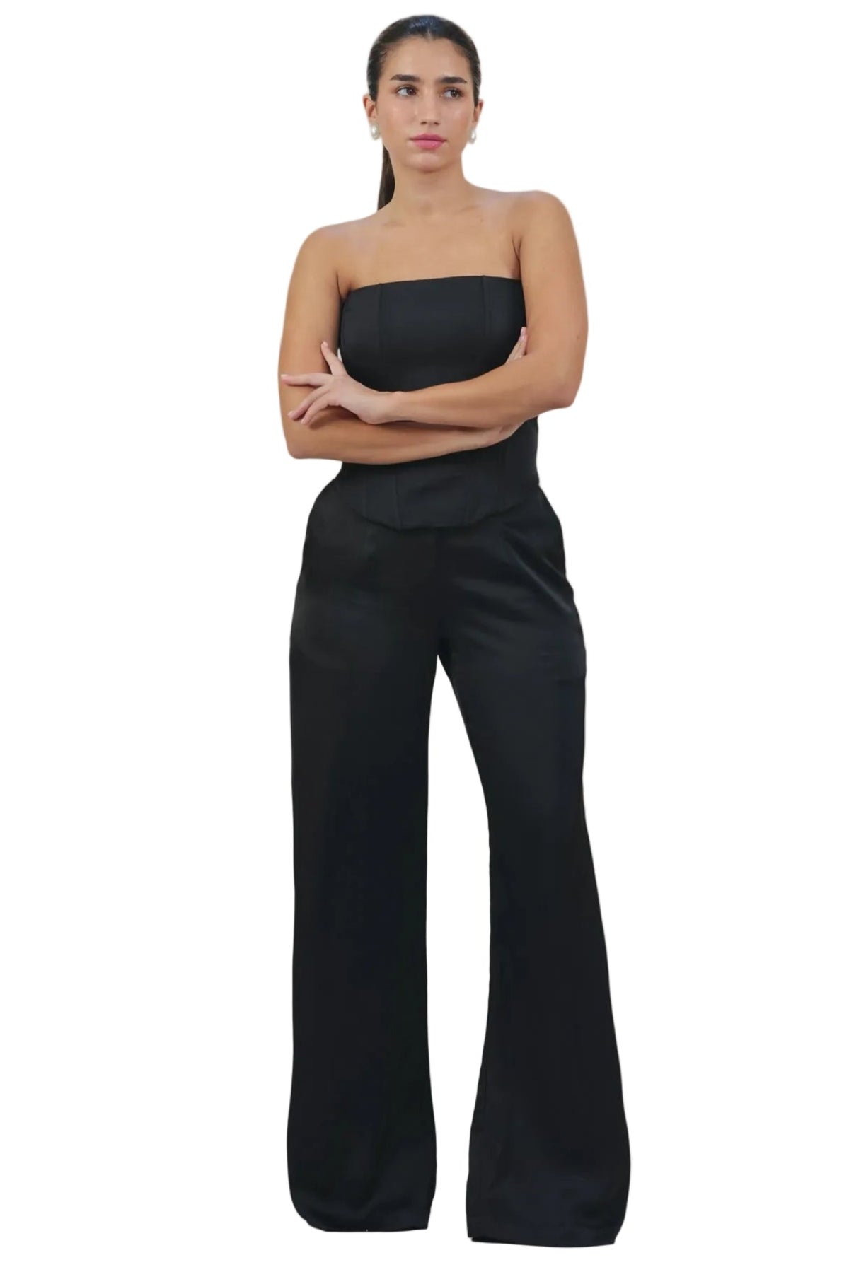 Woman wearing a black strapless top and wide-leg pants on a beige background