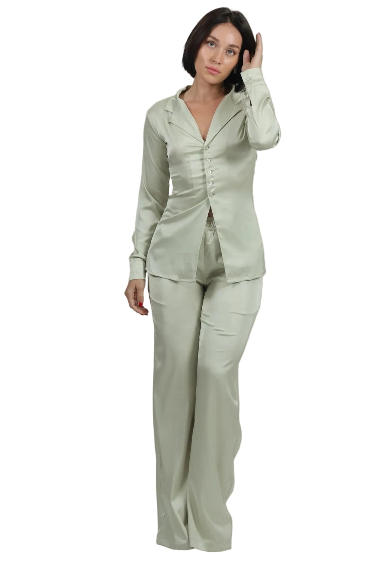 A woman modeling a light sage green two-piece pajama set with a long-sleeve button-front top and matching wide-leg pants, photographed against a plain white background.