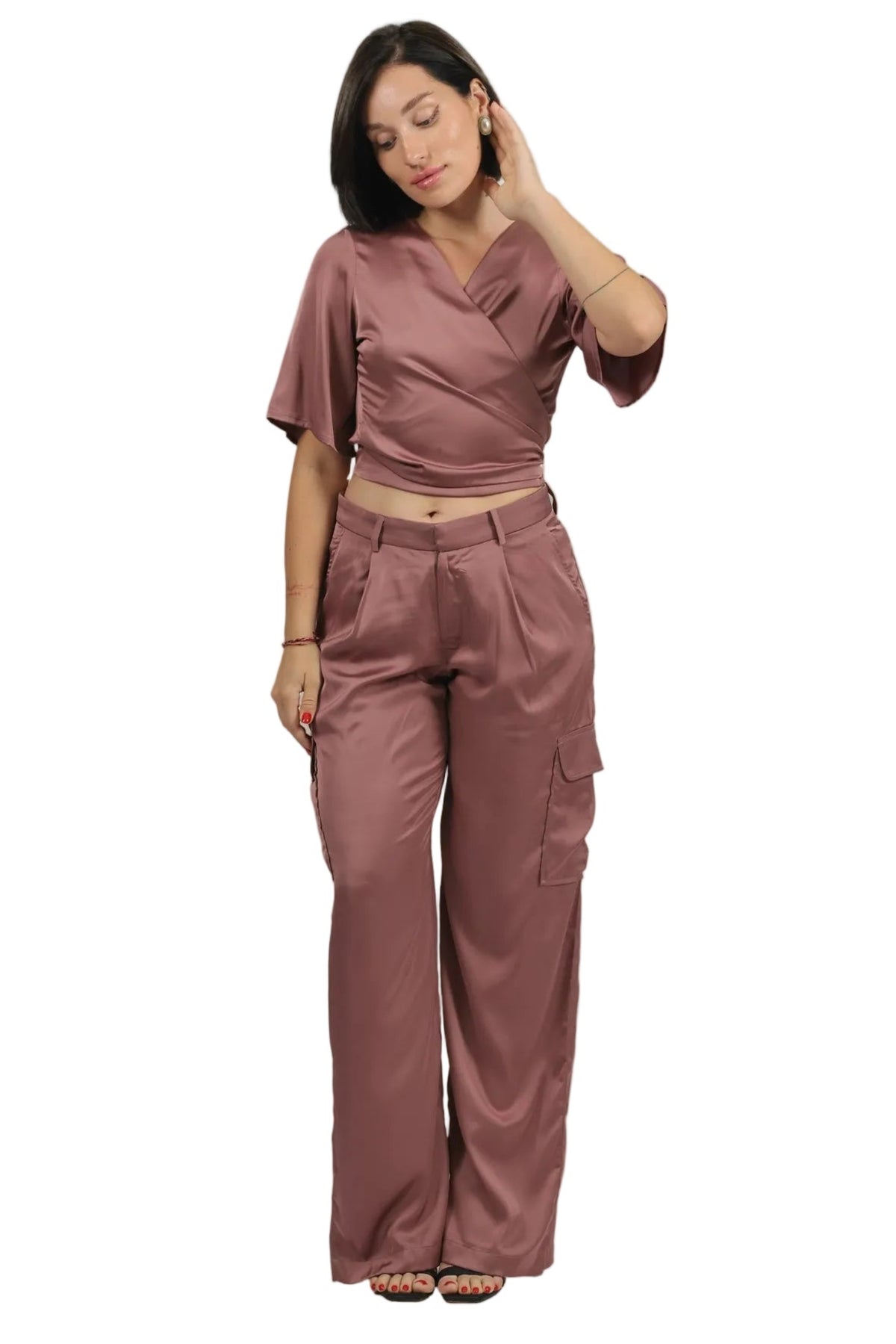 A woman modeling a matching dusty rose two-piece set consisting of a short-sleeve wrap-style crop top and high-waisted cargo pants, shot against a plain white background.