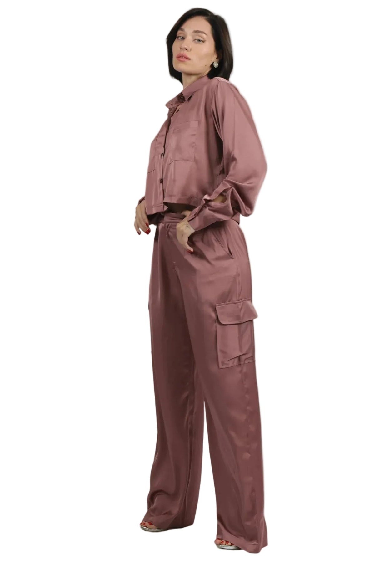 Woman wearing a matching pink outfit with a jacket and pants on a beige background