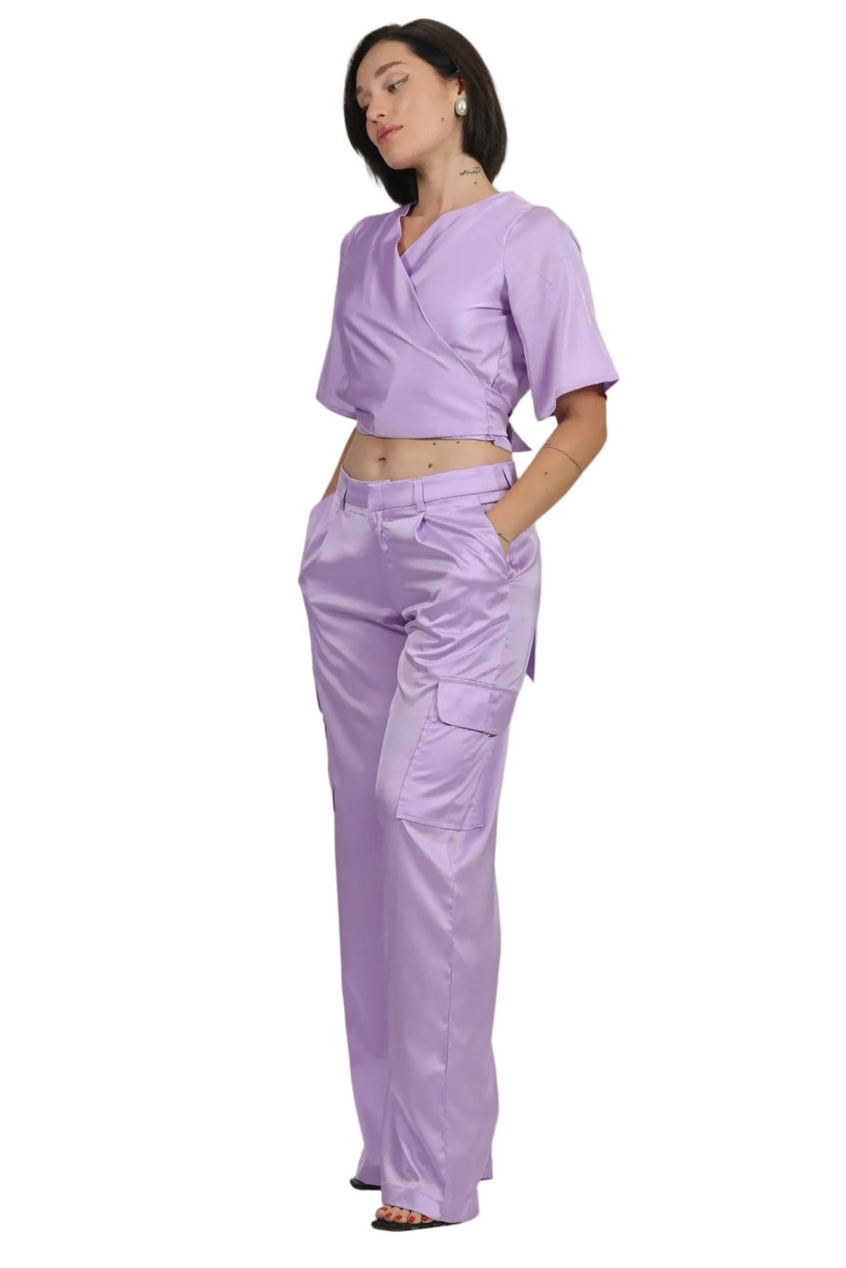 A woman modeling a matching lavender scrub set consisting of a short-sleeve V-neck crop top and high-waisted cargo pants, shown against a plain white background.