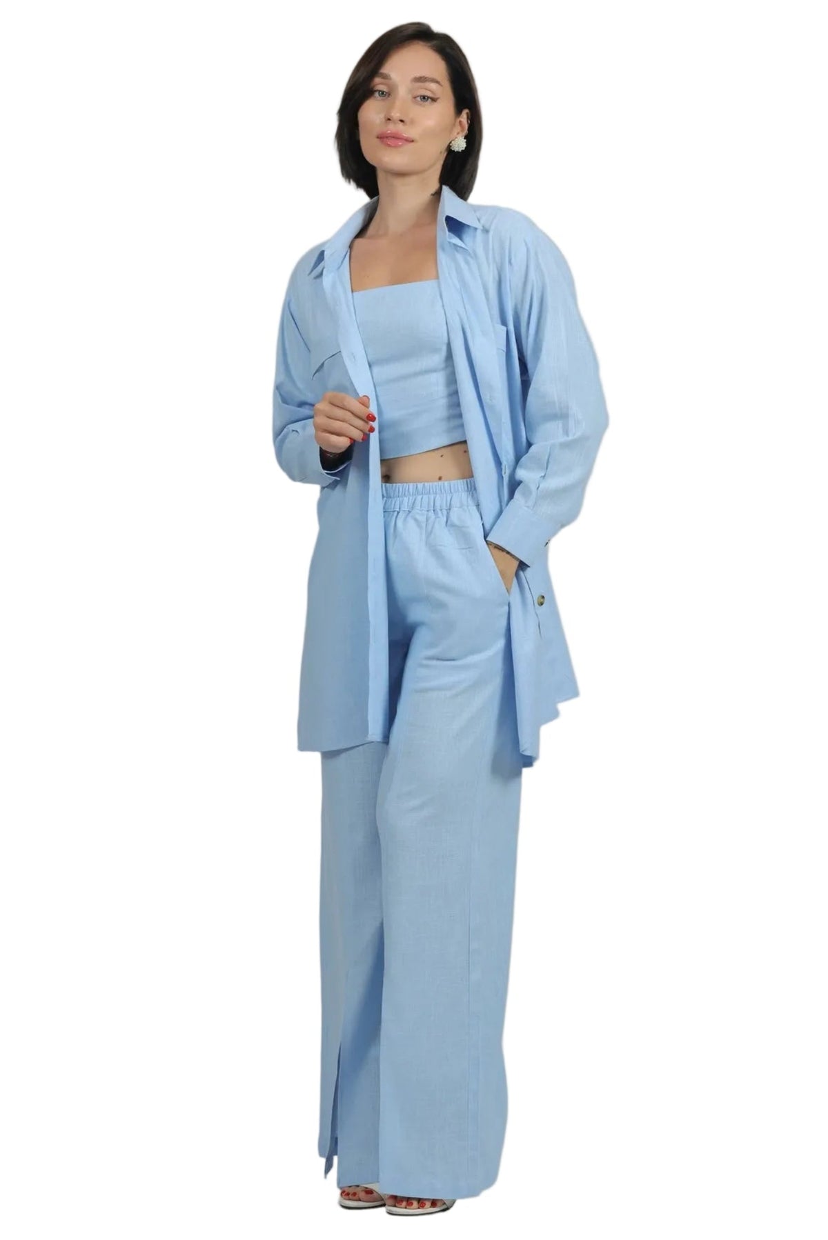 A woman modeling a light blue matching lounge set consisting of a cropped tank top, wide-leg pants, and an oversized button-up shirt, shot against a solid white background.