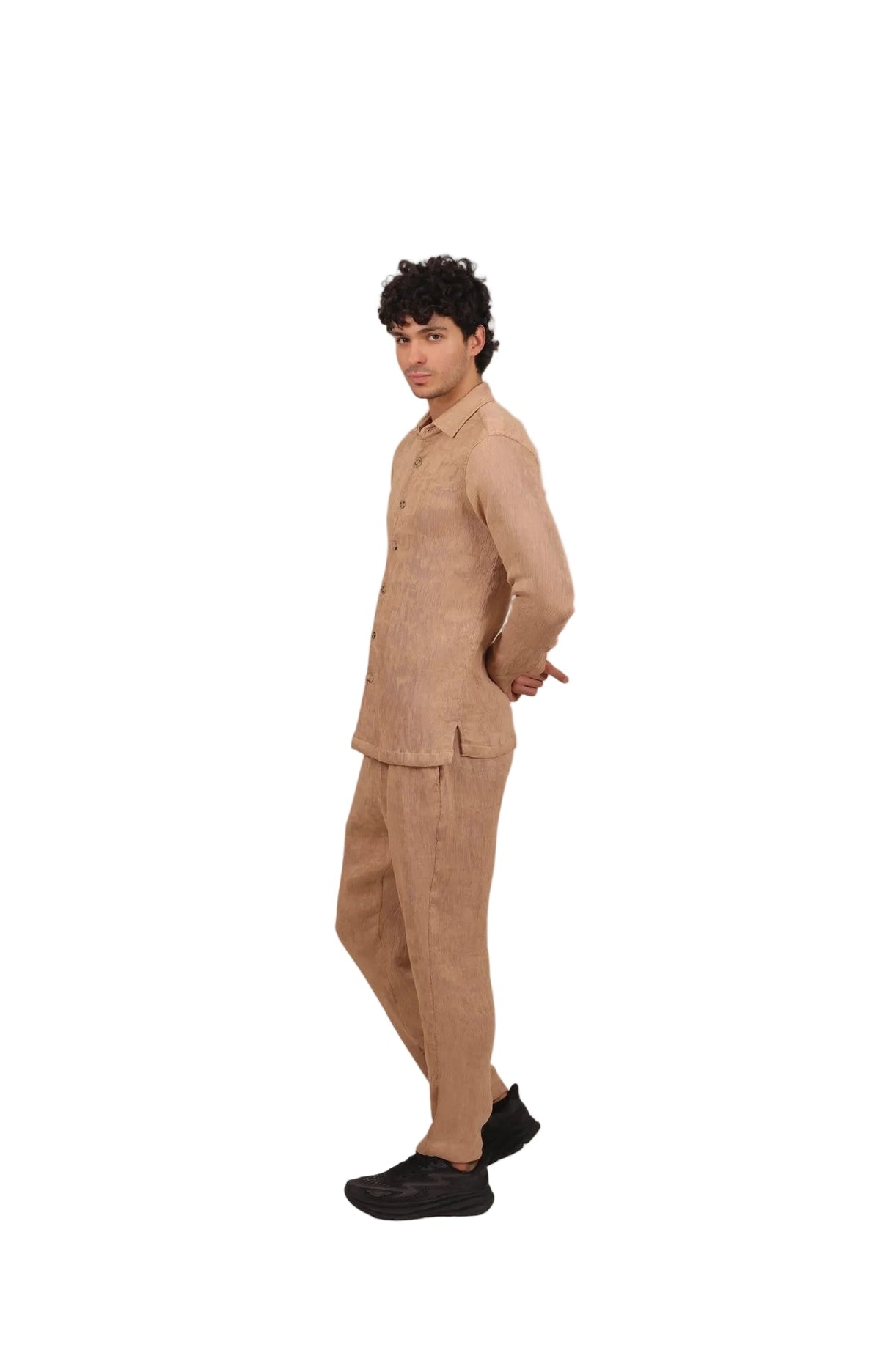 Person wearing a beige outfit standing against a plain background