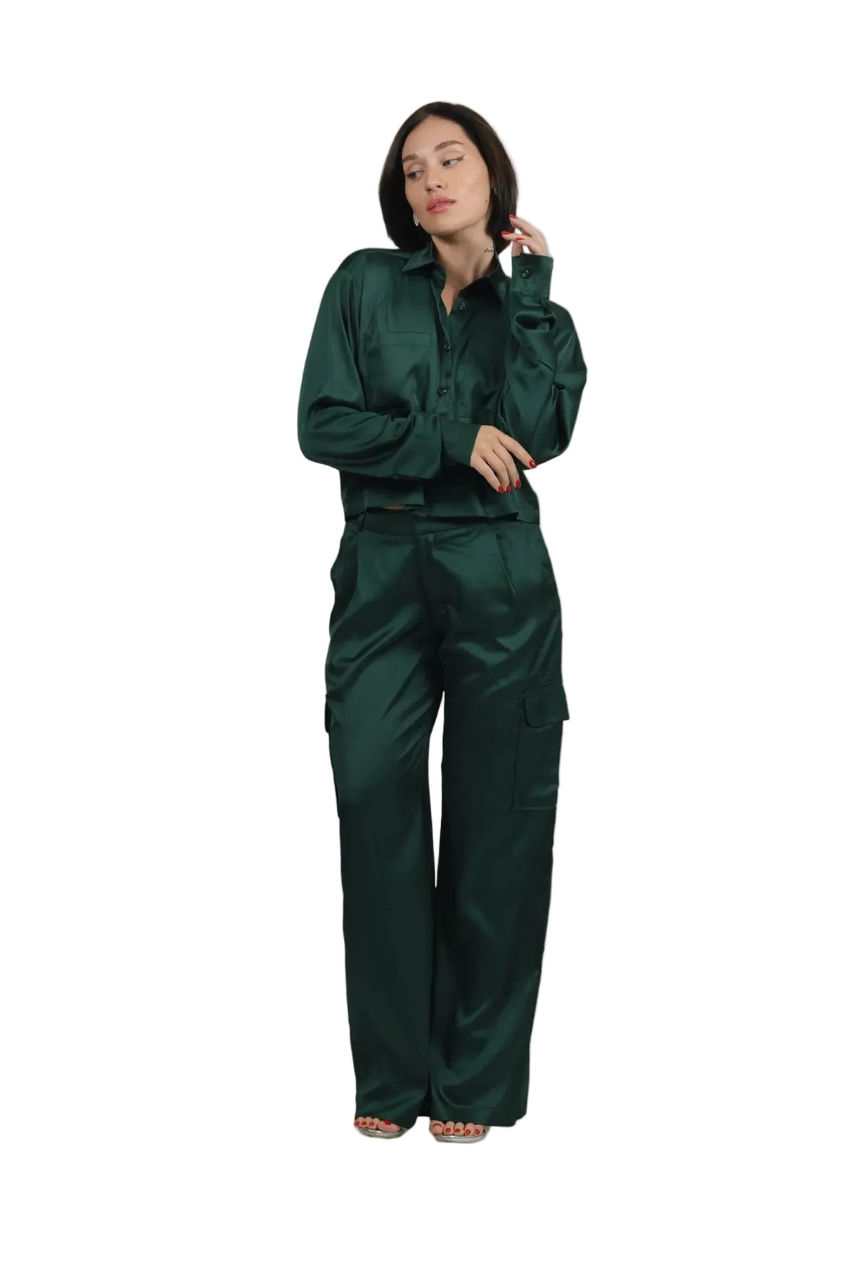 A woman modeling a dark green satin two-piece set consisting of a long-sleeve button-up shirt and matching wide-leg cargo pants, set against a solid beige background.