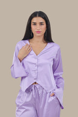 Woman wearing a light purple satin pajama set against a beige background