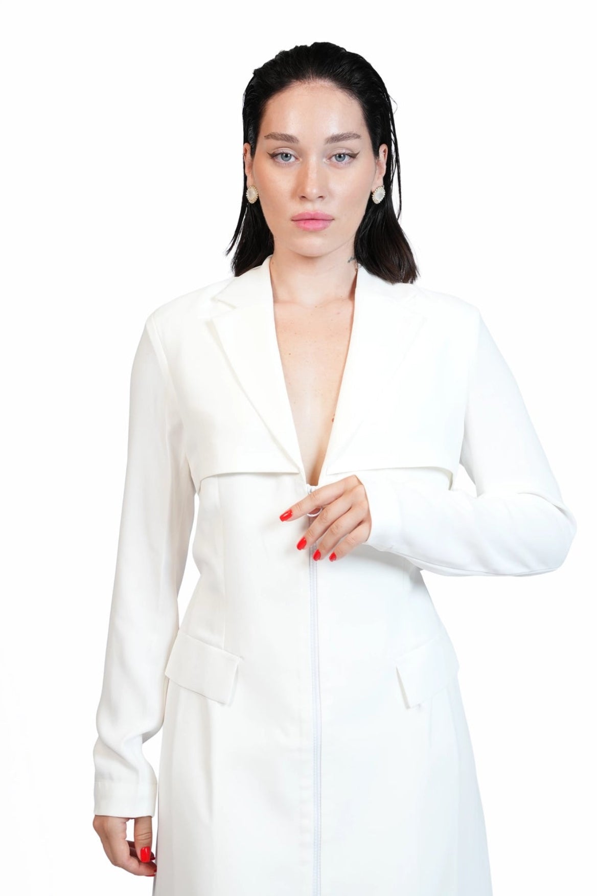 A woman modeling a white long-sleeve blazer-style dress with a deep V-neckline and front closure, photographed against a plain white studio background.