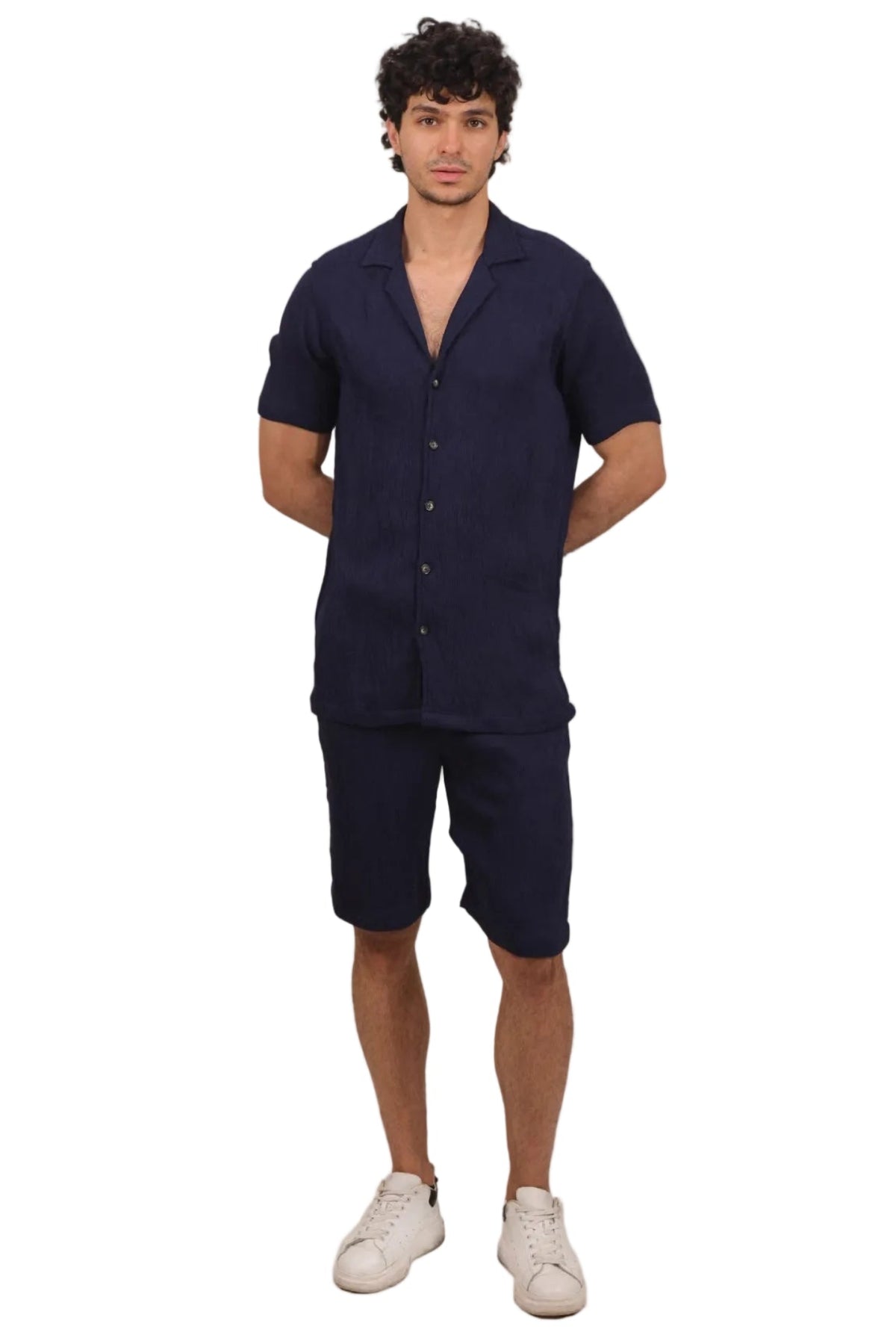 Man wearing a navy blue outfit with a shirt and shorts on a beige background