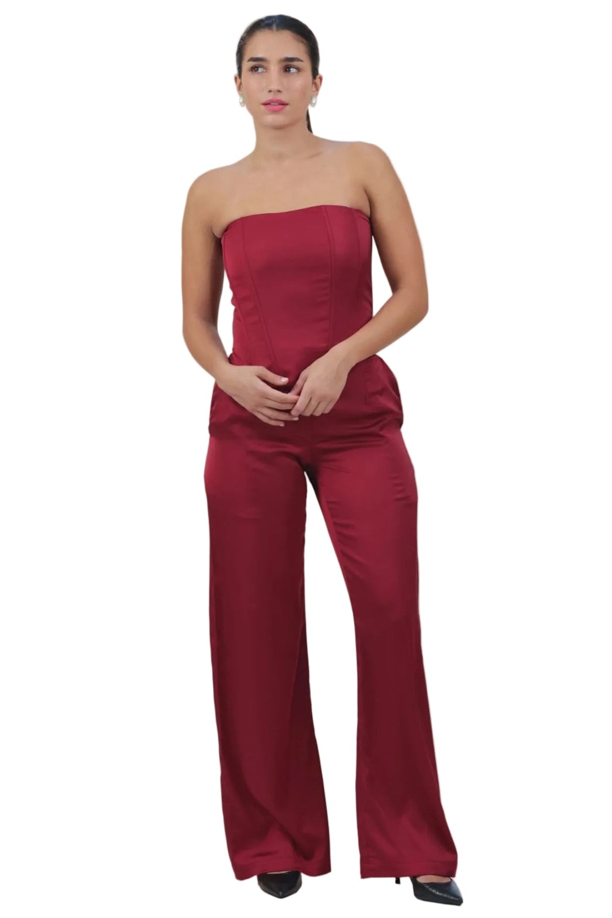 A woman modeling a strapless red jumpsuit with wide legs, standing against a plain white background.