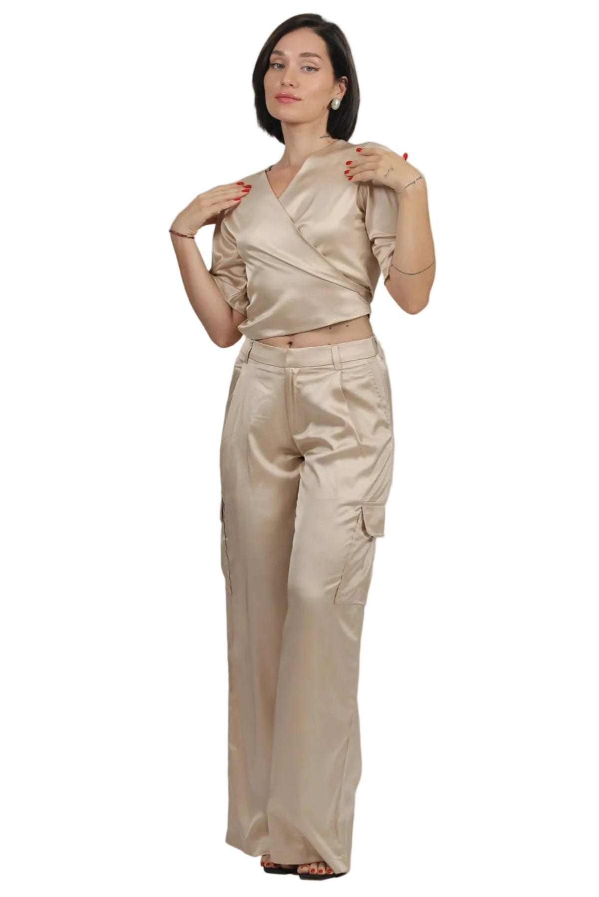 A woman modeling a matching two-piece outfit consisting of a champagne gold satin wrap-style crop top and wide-leg trousers, set against a plain white background.