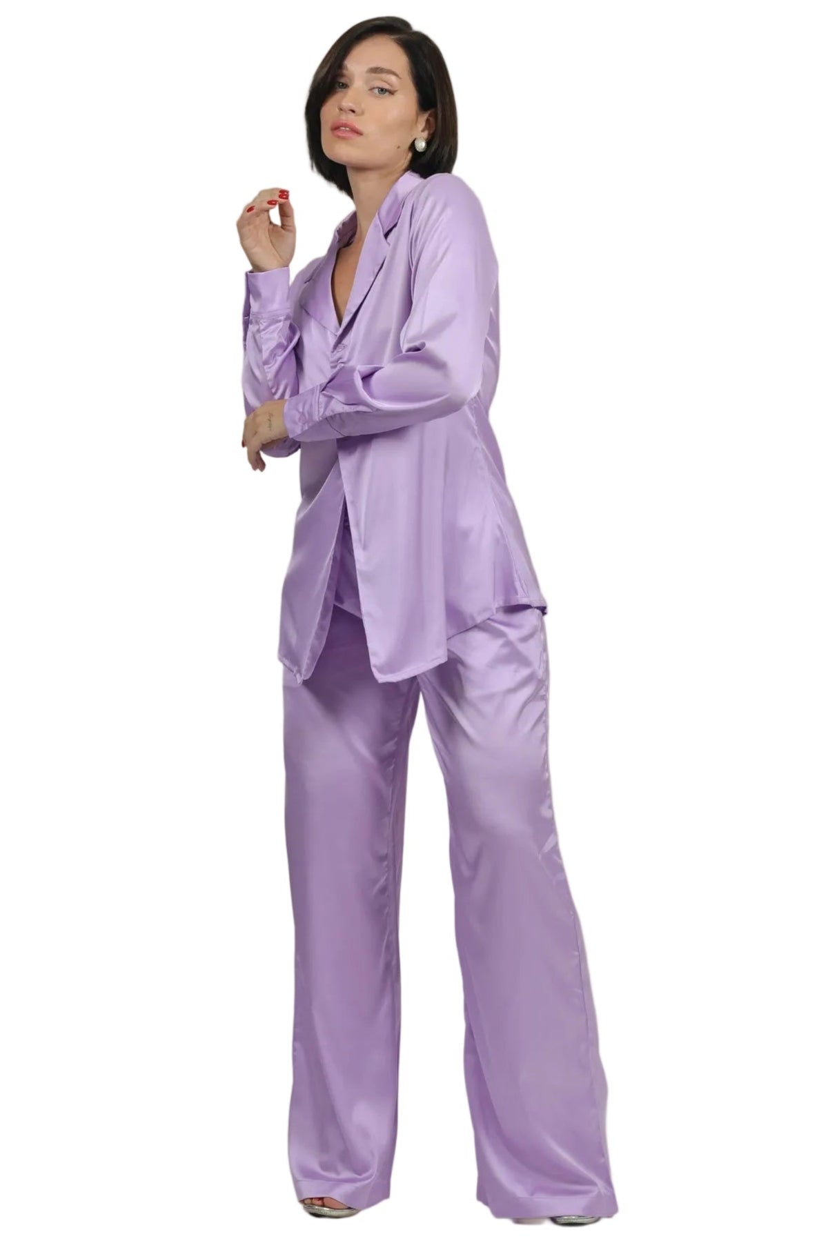 A woman modeling a lavender satin pajama set consisting of a long-sleeve button-up shirt and matching wide-leg pants, set against a plain white background.