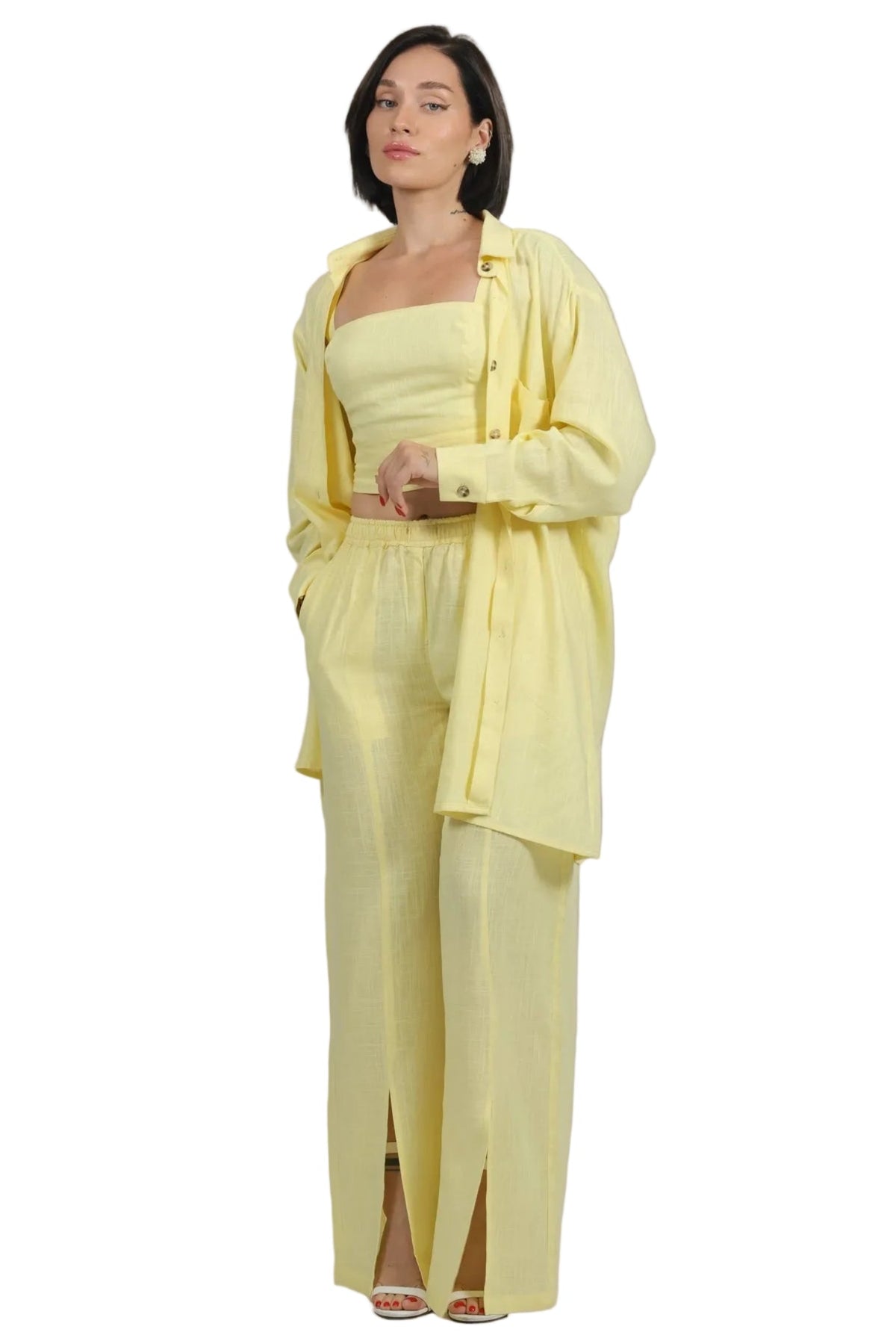 A woman modeling a light yellow three-piece outfit consisting of a strapless tube top, matching wide-leg trousers with front slits, and a matching open-front jacket, set against a plain white background.