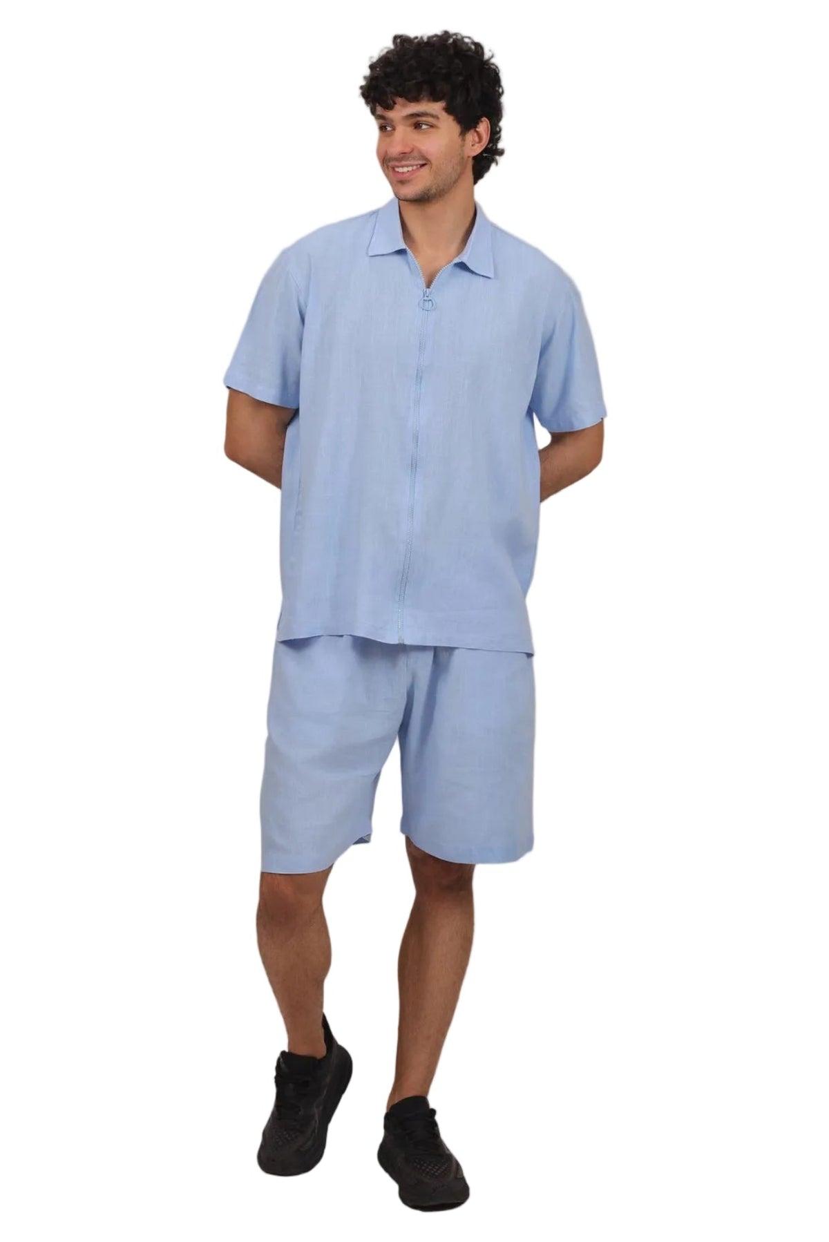 A man modeling a light blue short-sleeve button-up shirt and matching light blue shorts against a plain white background.