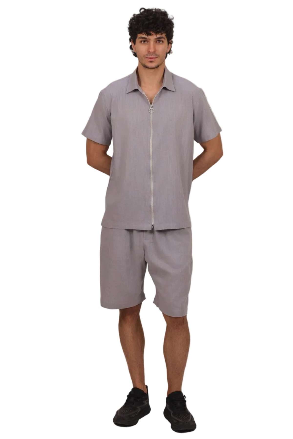 A man modeling a light gray short-sleeve button-up shirt and matching shorts set, standing against a plain white background.