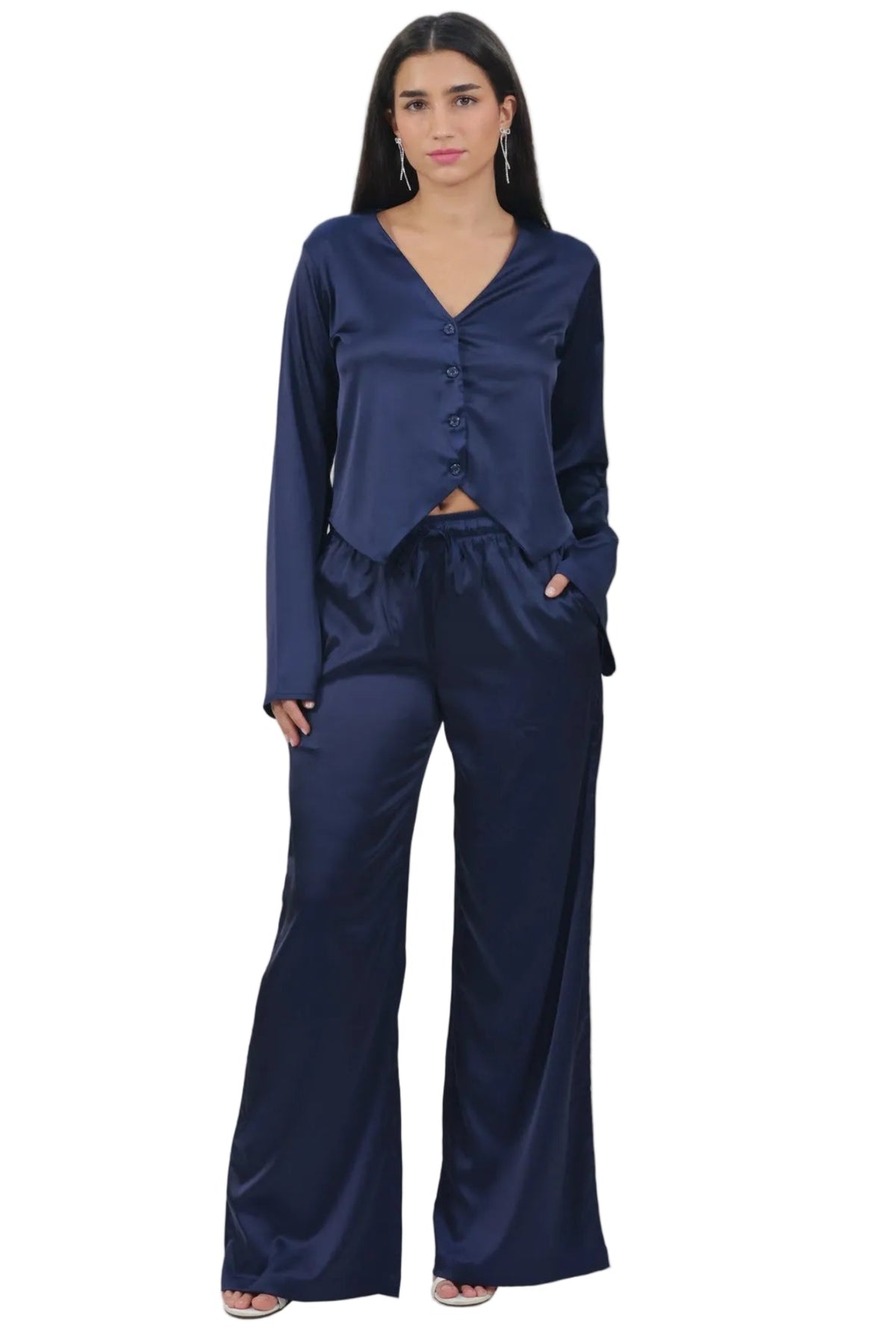 A woman modeling a matching navy blue two-piece lounge set consisting of a long-sleeve V-neck top with a ruffled hem and matching wide-leg pants, shot against a plain white background.