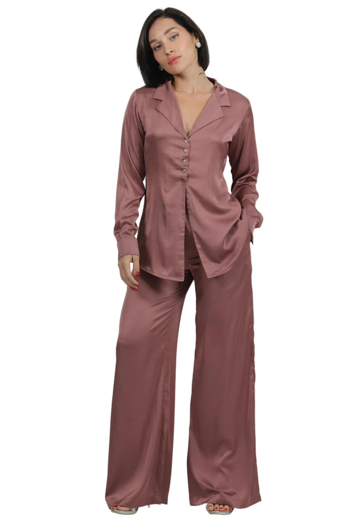 A woman modeling a two-piece satin pajama set in a dusty rose color, consisting of a long-sleeve button-up shirt and matching wide-leg pants, set against a plain white background.