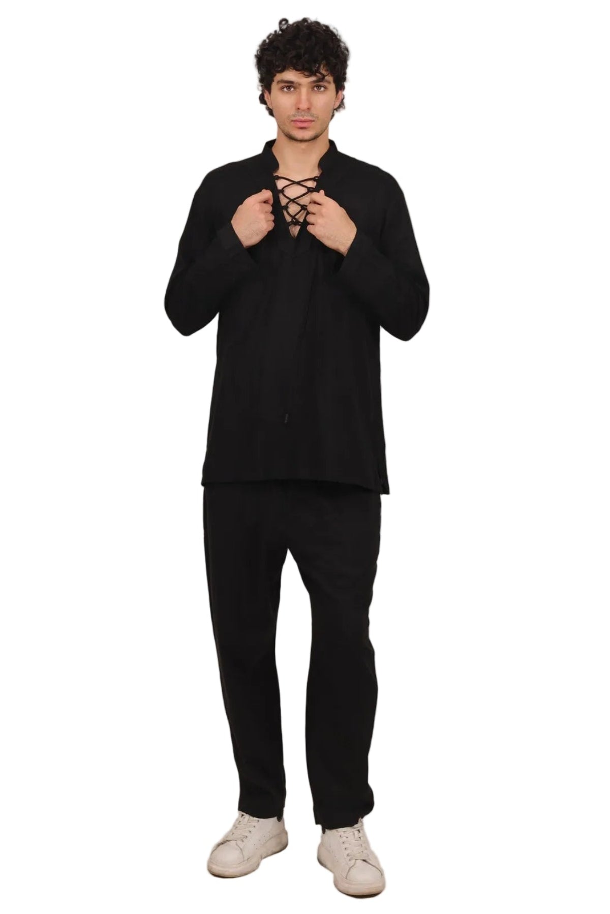 A man wearing a black long-sleeve button-up shirt with lace-up detailing at the collar, paired with black pants and off-white sneakers, standing against a solid white background.
