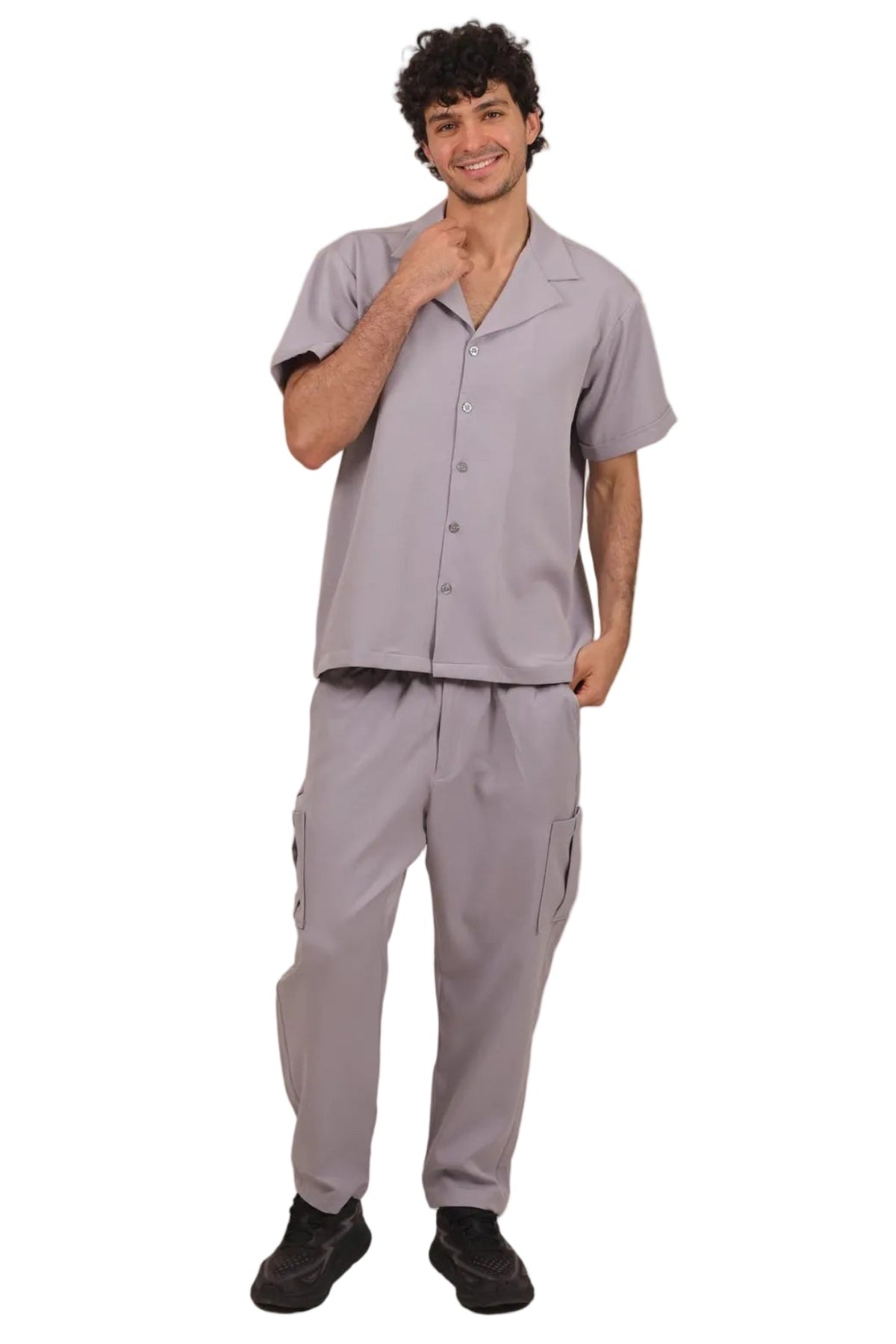 A man modeling a light gray scrub set consisting of a short-sleeve button-up shirt and matching cargo pants, standing against a solid white background.