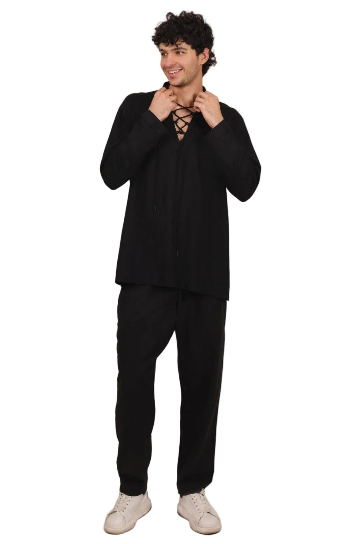 A man modeling a black two-piece costume set consisting of a long-sleeve top with a lace-up front and matching black pants, paired with white sneakers, against a solid white background.