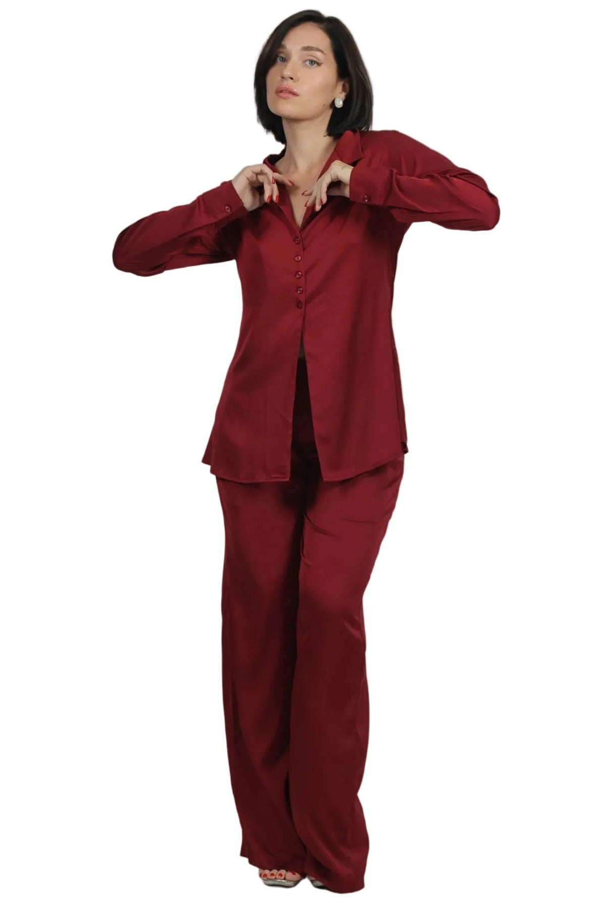 A woman modeling a matching two-piece pajama set in deep burgundy red, consisting of a long-sleeve button-up top and wide-leg pants, set against a plain white background.