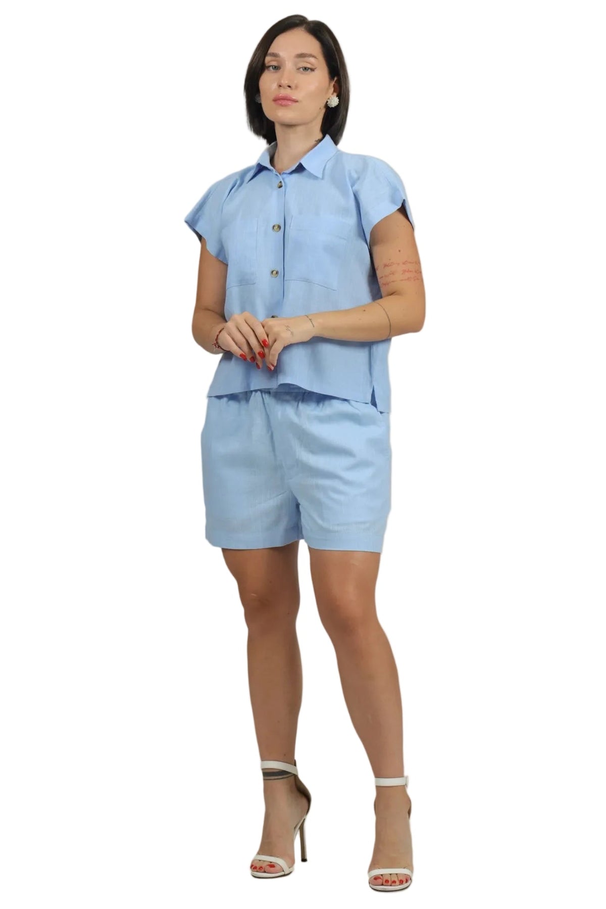 Woman wearing a light blue outfit with a matching top and shorts on a beige background