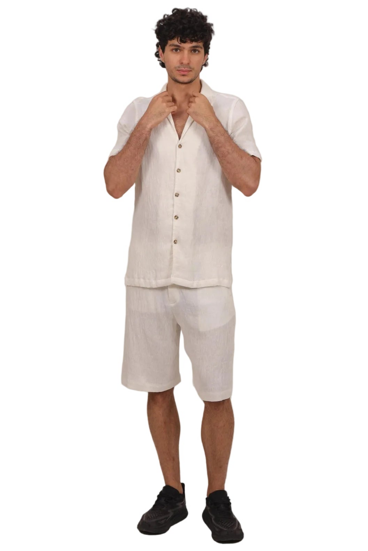 A man modeling a matching off-white linen short-sleeve button-up shirt and shorts set, paired with black shoes, against a solid white background.