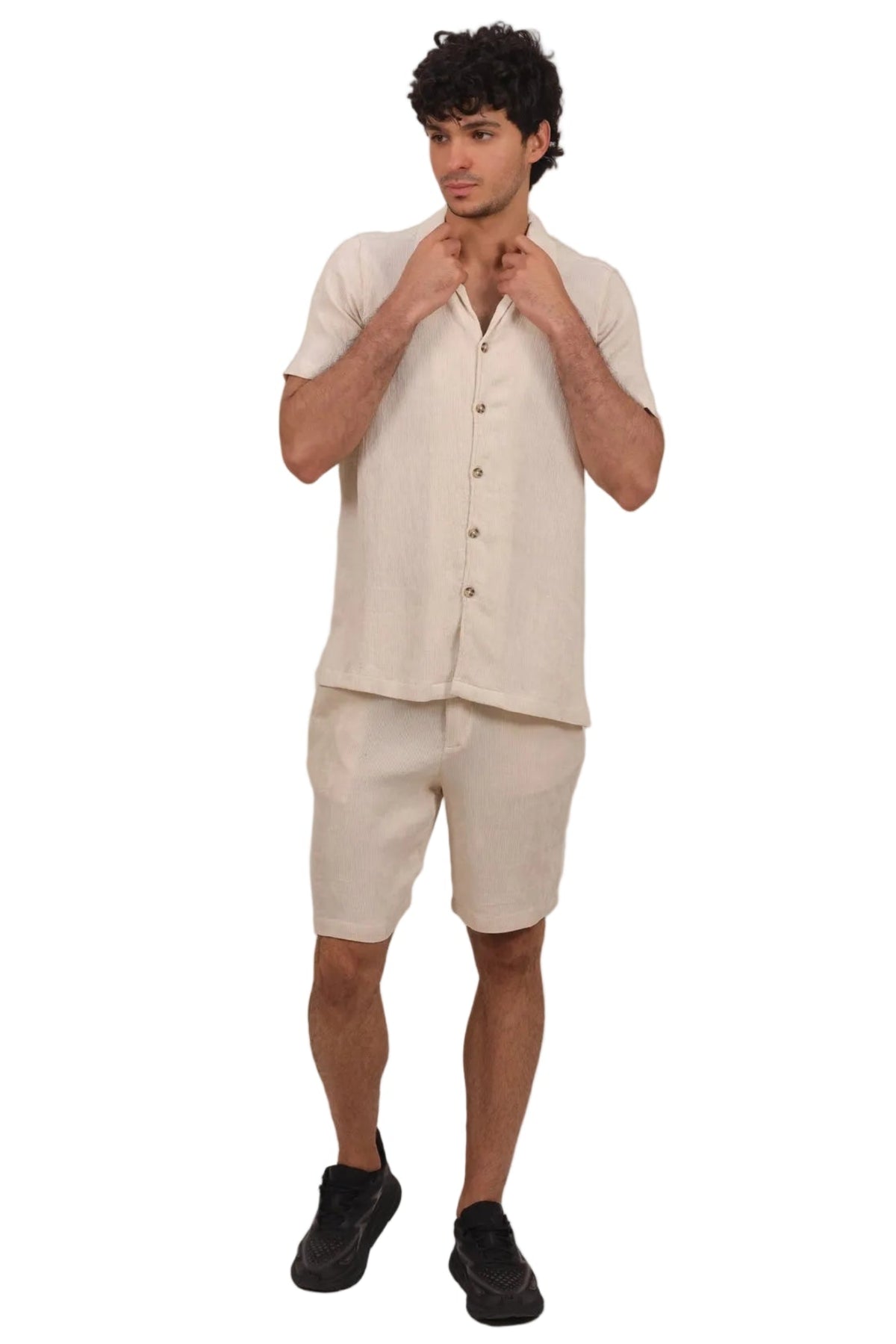 A man modeling a light beige linen short-sleeve button-up shirt and matching linen shorts against a solid white background.