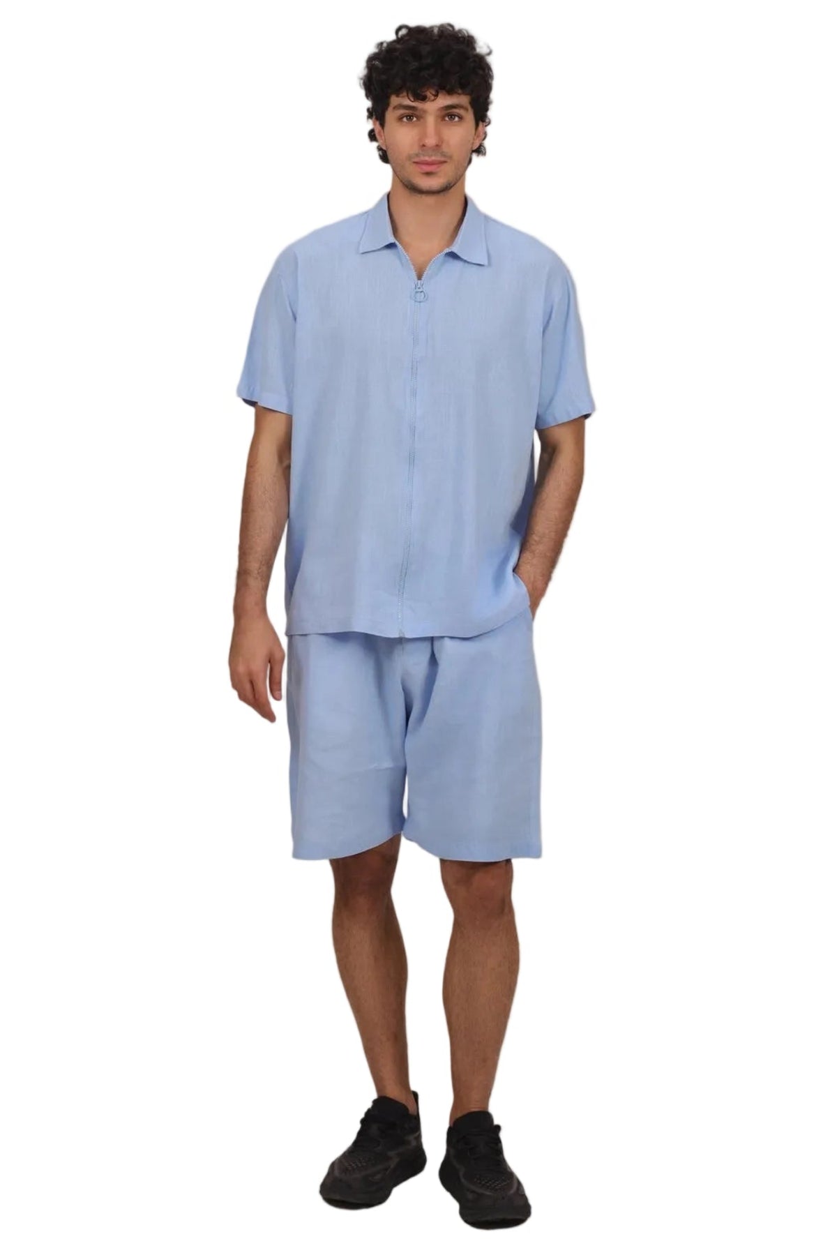 A man modeling a light blue short-sleeve button-up shirt and matching light blue shorts against a solid white background.
