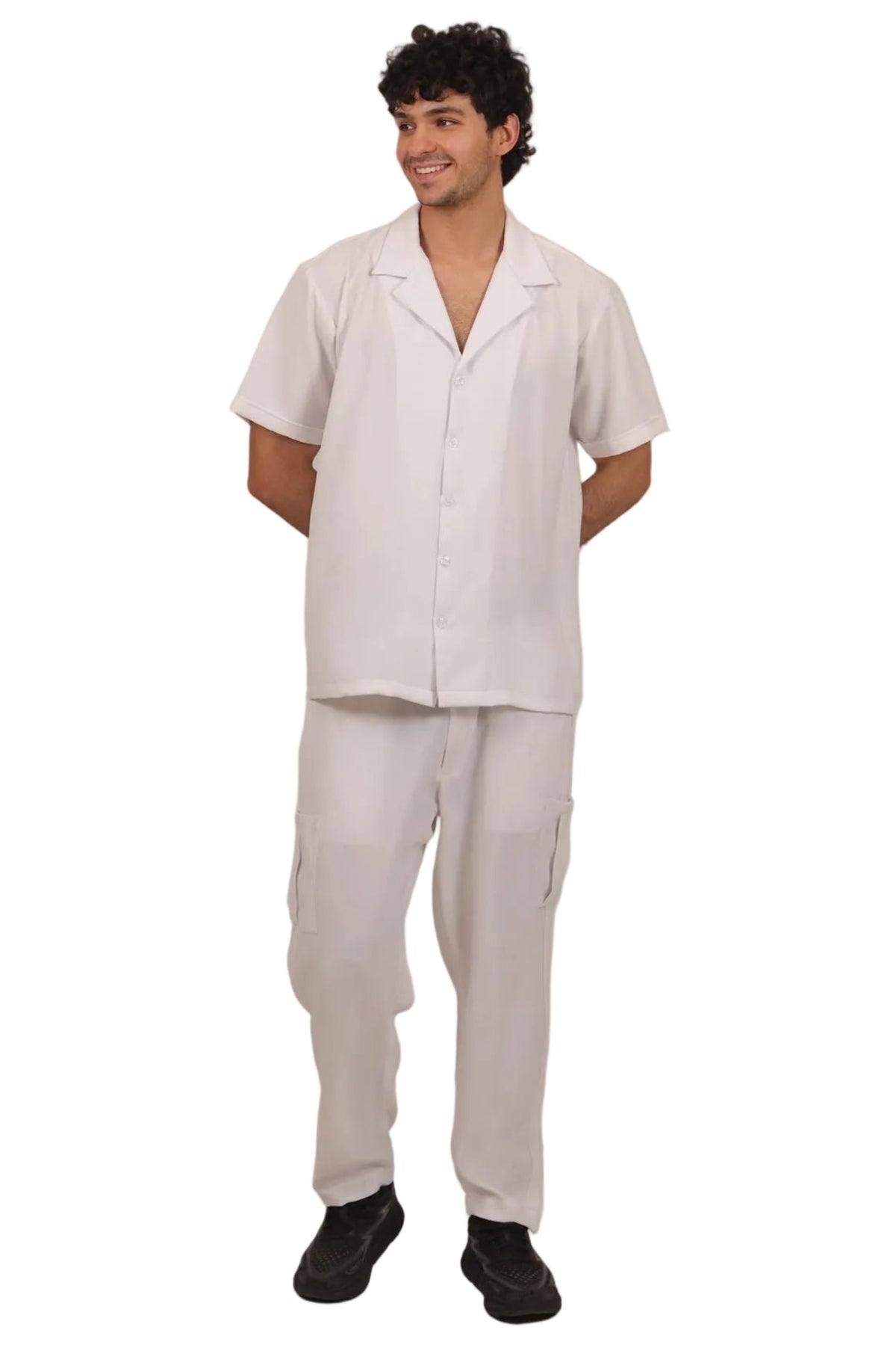 A man modeling a white short-sleeve button-up shirt and matching white trousers against a solid white background.