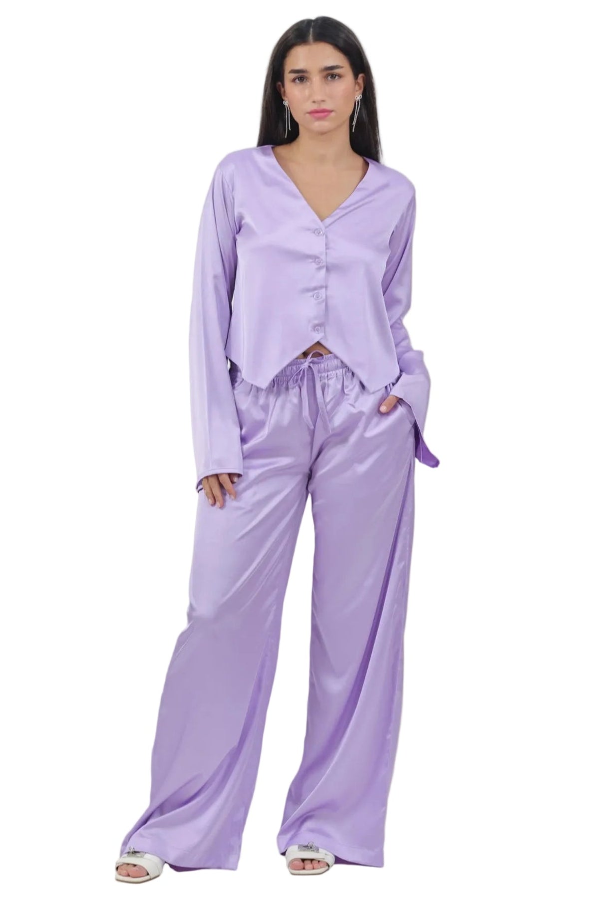 A woman modeling a lavender satin pajama set consisting of a long-sleeve button-front top and matching wide-leg pants, photographed against a plain white background.