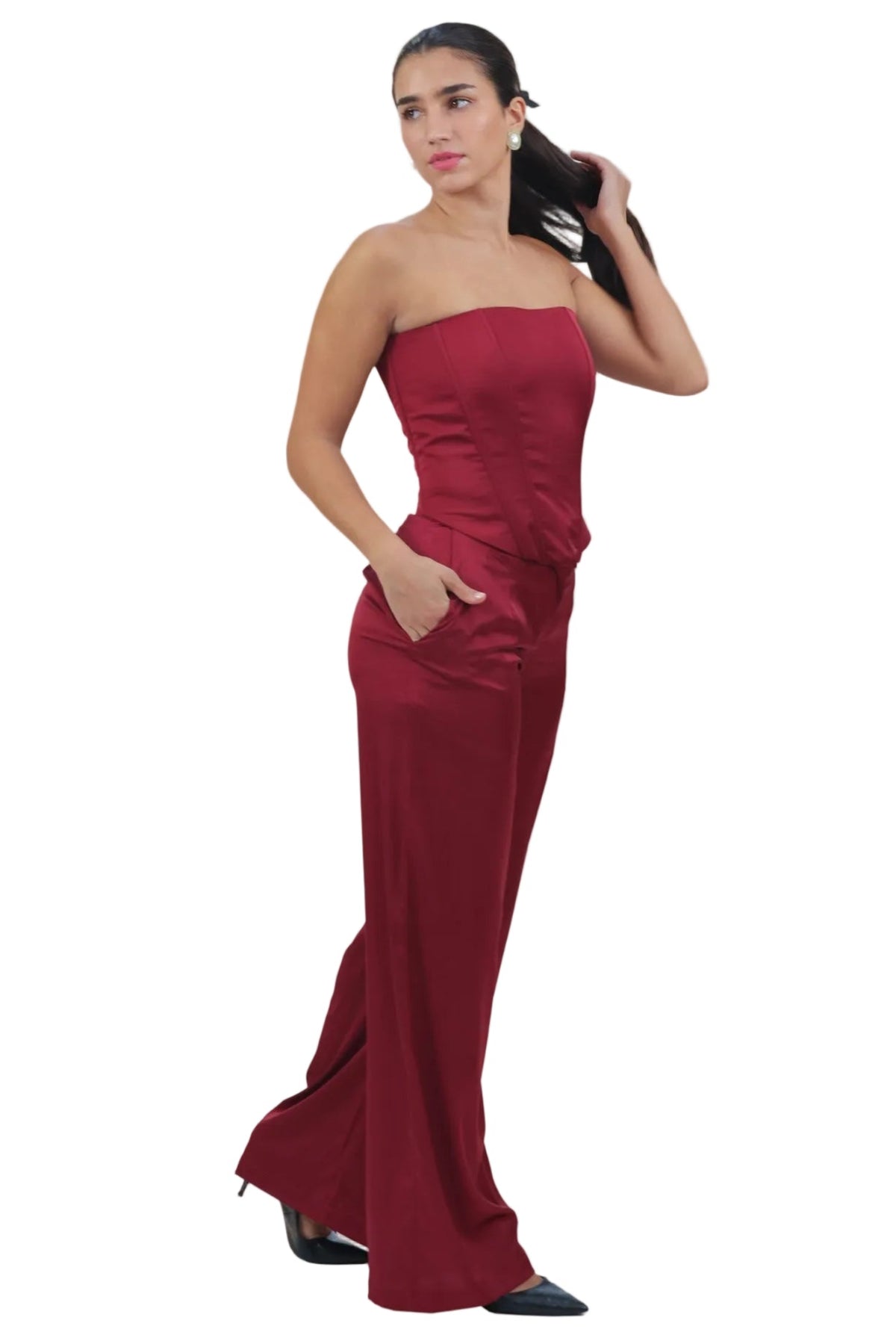 A woman modeling a strapless, floor-length burgundy gown with side pockets, standing against a plain white background.