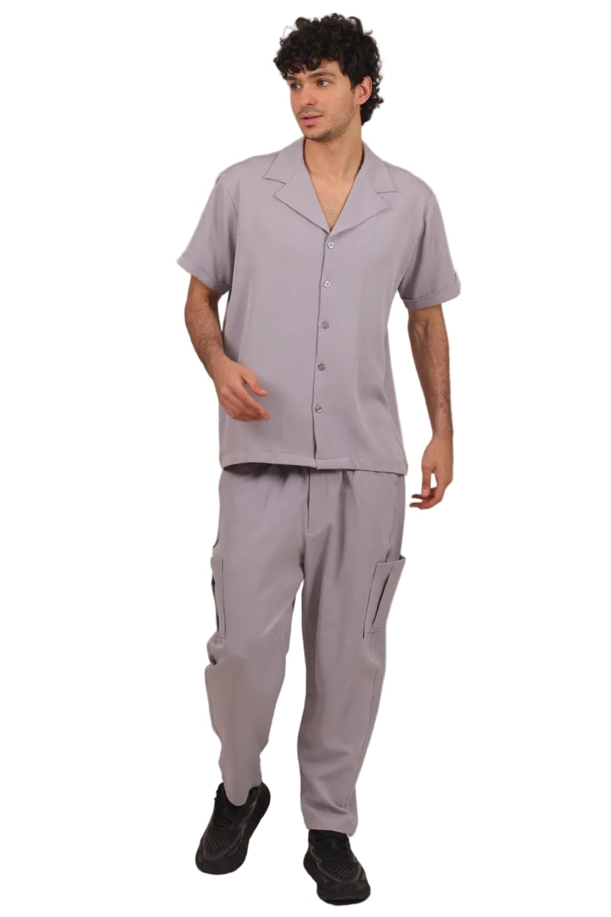 A man modeling a light gray short-sleeve button-up scrub top and matching cargo pants against a plain white background.