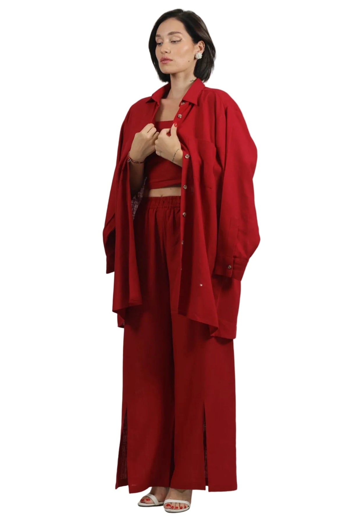 A woman modeling a matching red three-piece outfit consisting of a cropped tank top, wide-leg trousers, and an oversized button-up shirt, set against a plain white background.