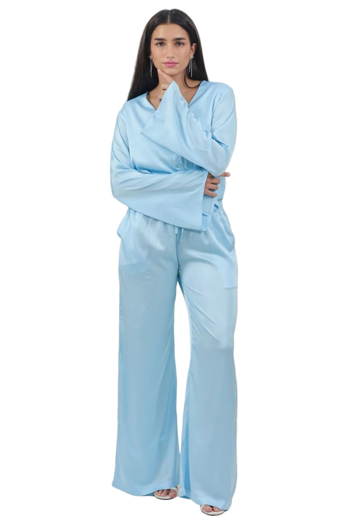 A woman modeling a light blue two-piece lounge set consisting of a long-sleeve V-neck top and matching wide-leg pants, photographed against a solid white background.