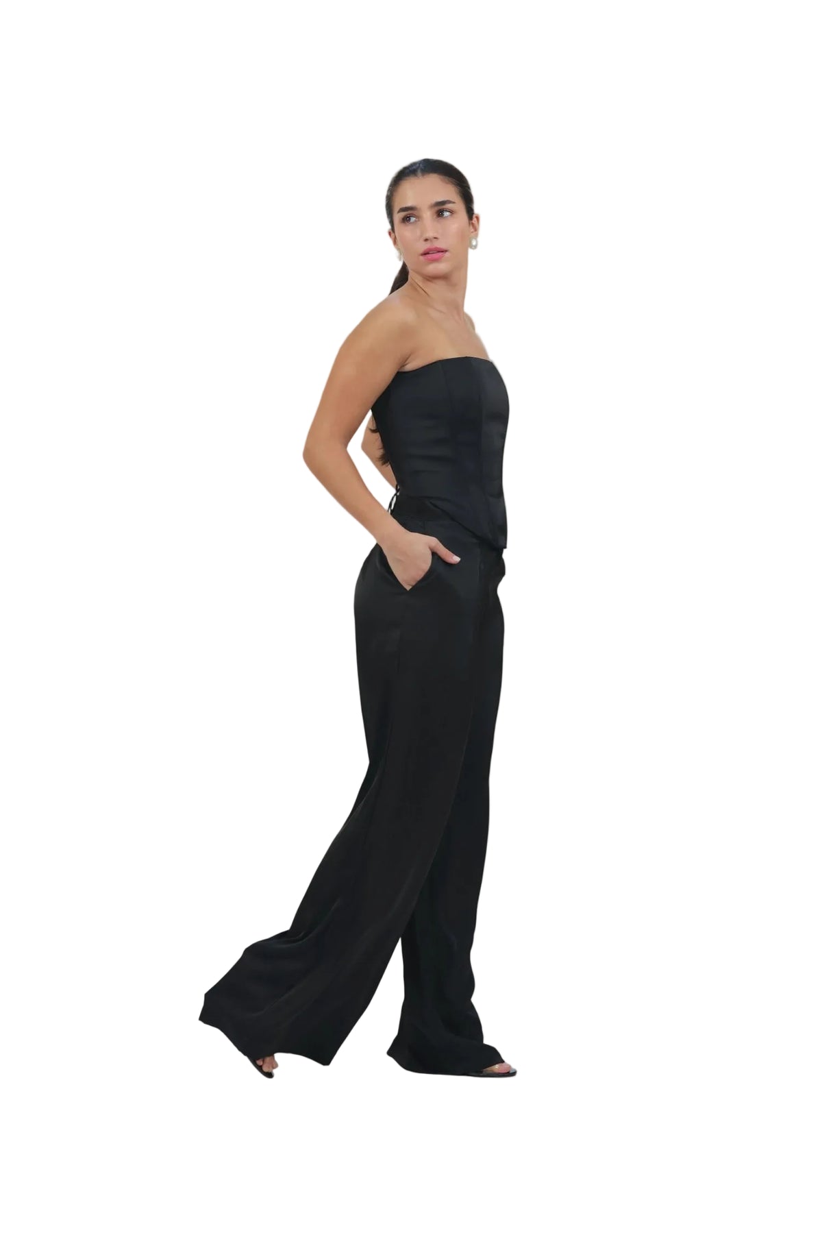 Woman wearing a black strapless top and wide-leg pants on a beige background