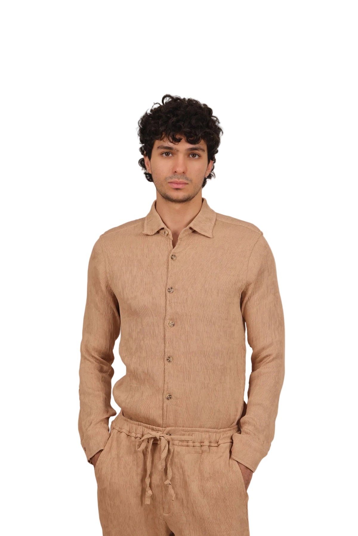 Man wearing a brown button-up shirt and pants against a beige background