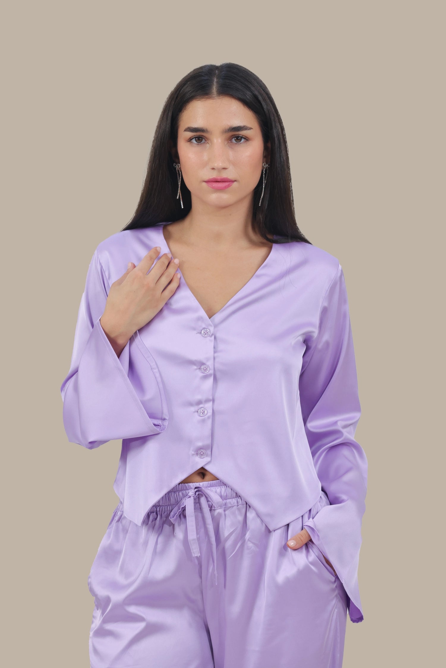 Woman wearing a light purple satin pajama set against a beige background