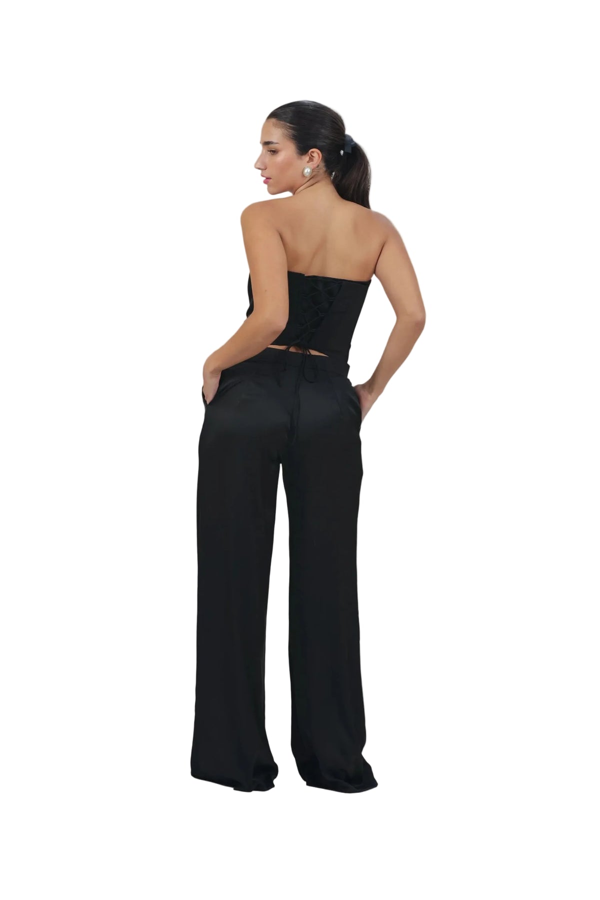 Woman wearing a black strapless jumpsuit on a beige background