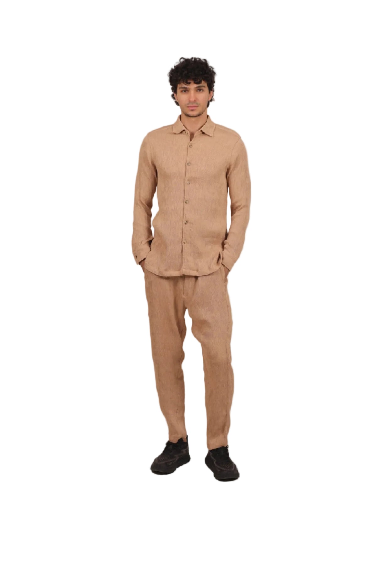 Man wearing a beige shirt and pants standing against a beige background