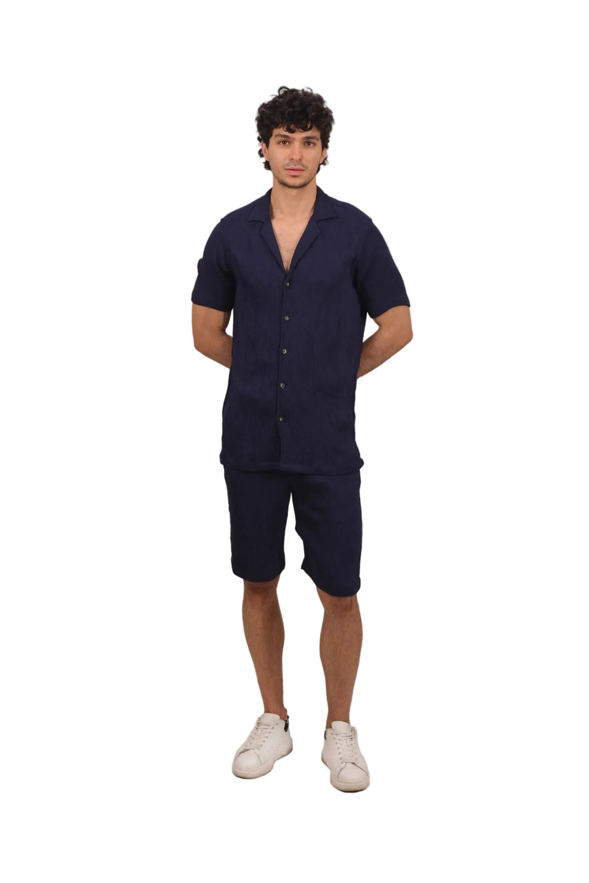 Man wearing a navy blue outfit with a shirt and shorts on a beige background